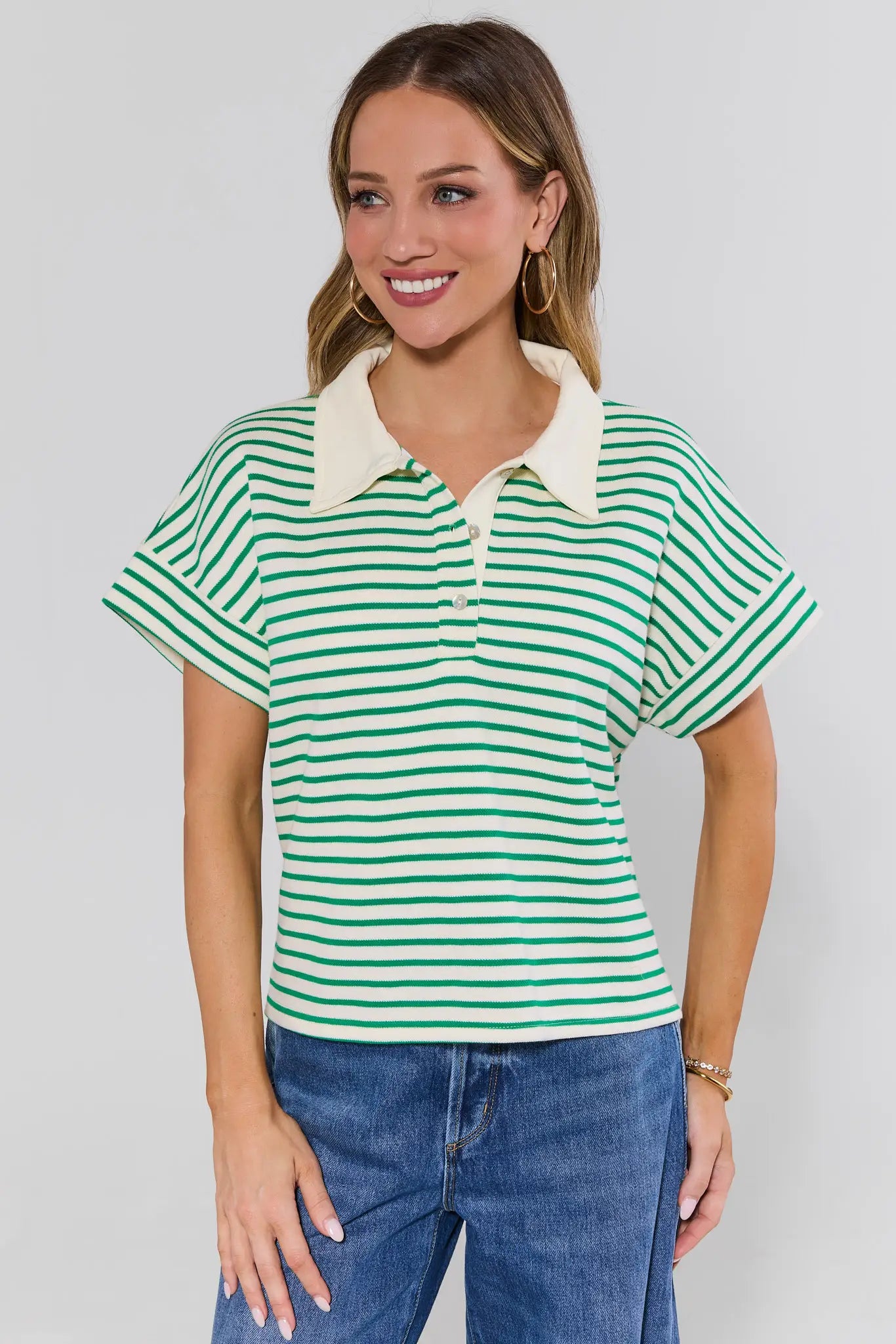 Woman wearing a green and white striped polo shirt with a plain background