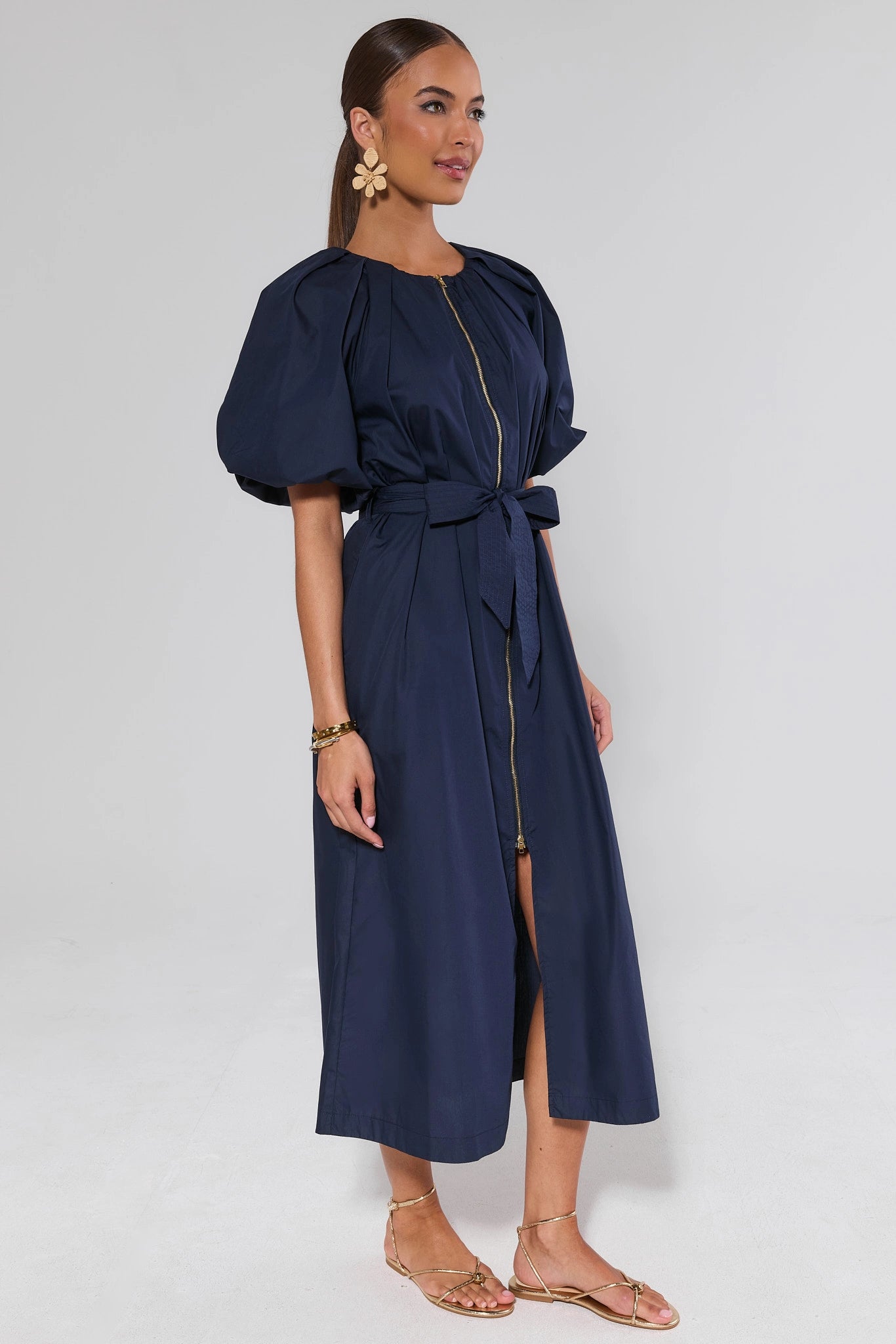 side shot Woman wearing a navy blue dress with puff sleeves on a white background