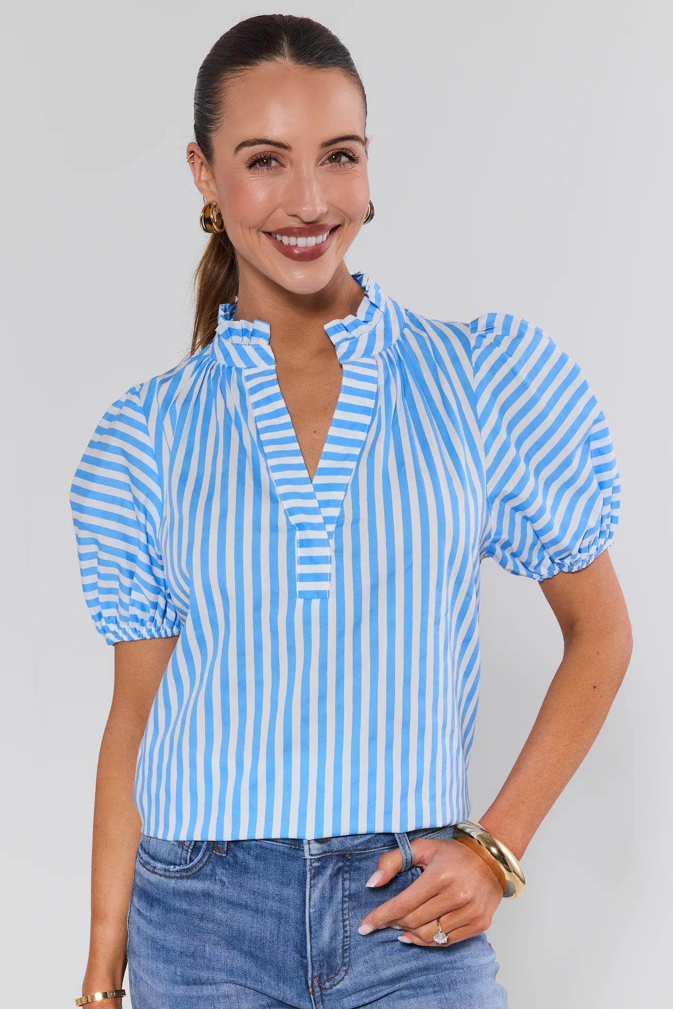 Woman wearing a blue and white striped blouse with short sleeves on a plain background