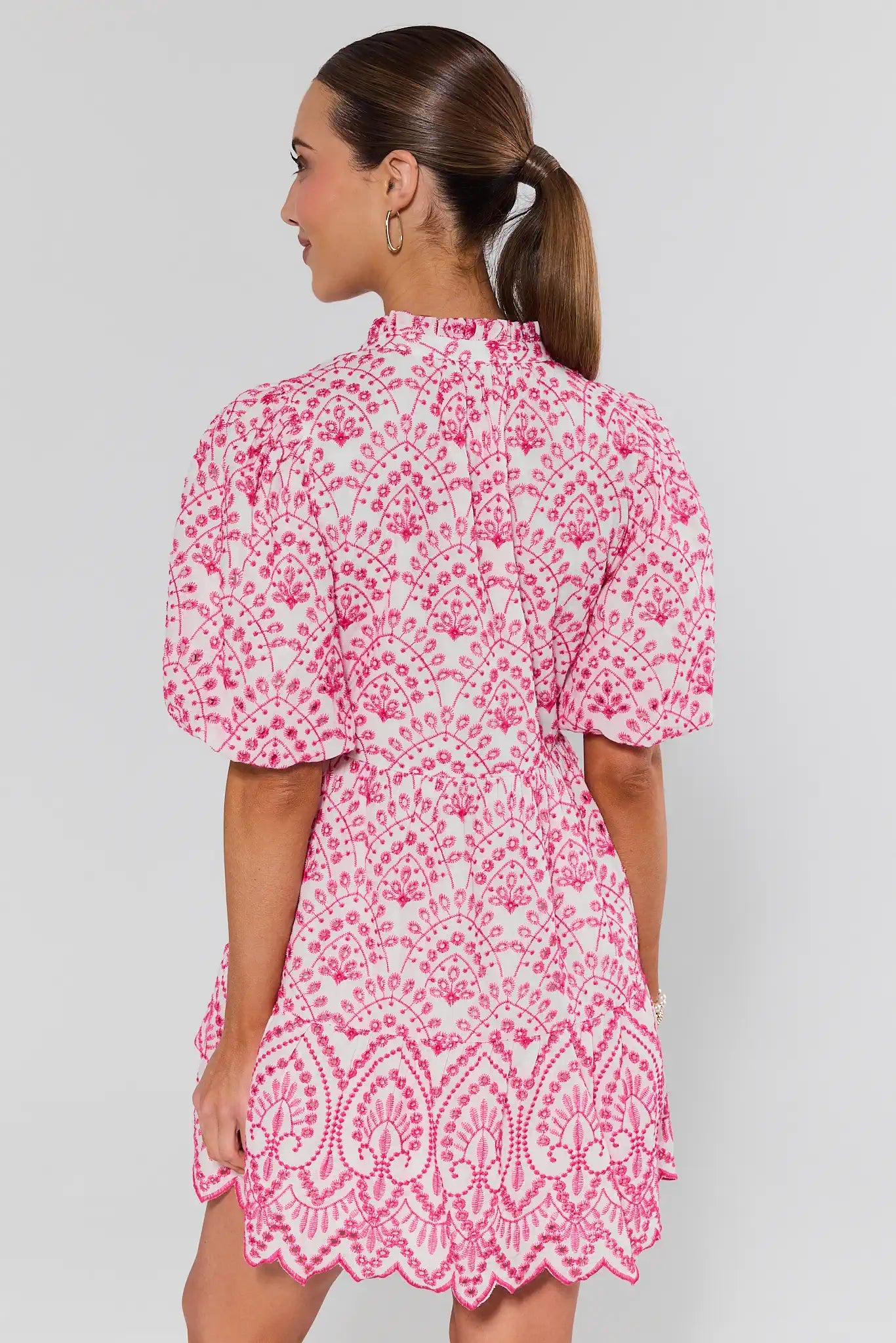 Woman wearing a pink and white floral dress against a gray background