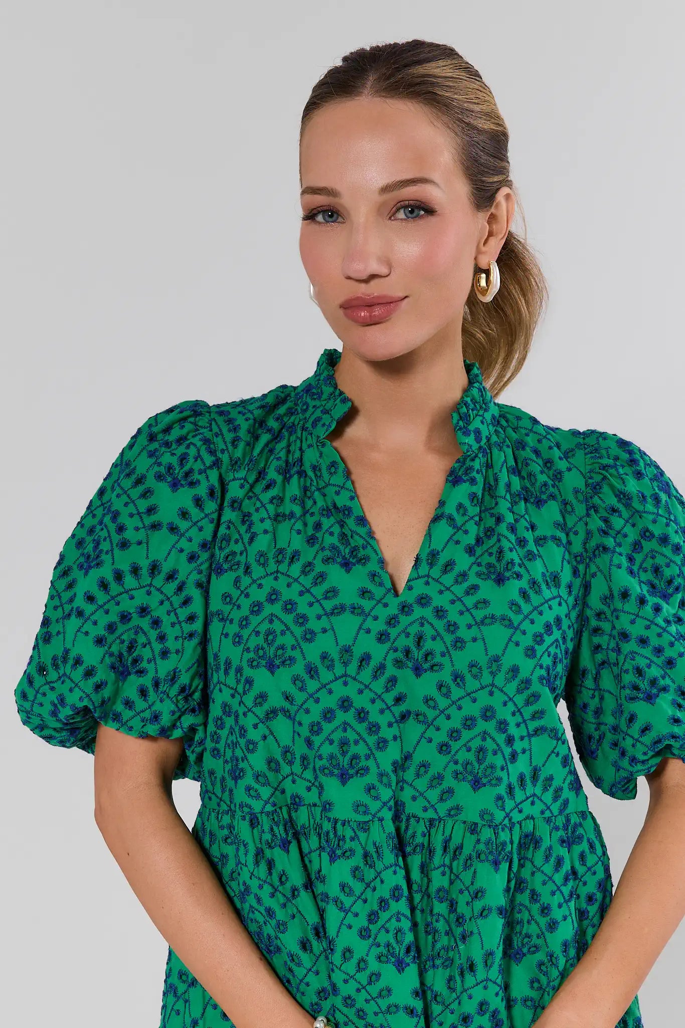 Woman wearing a green patterned dress against a plain background
