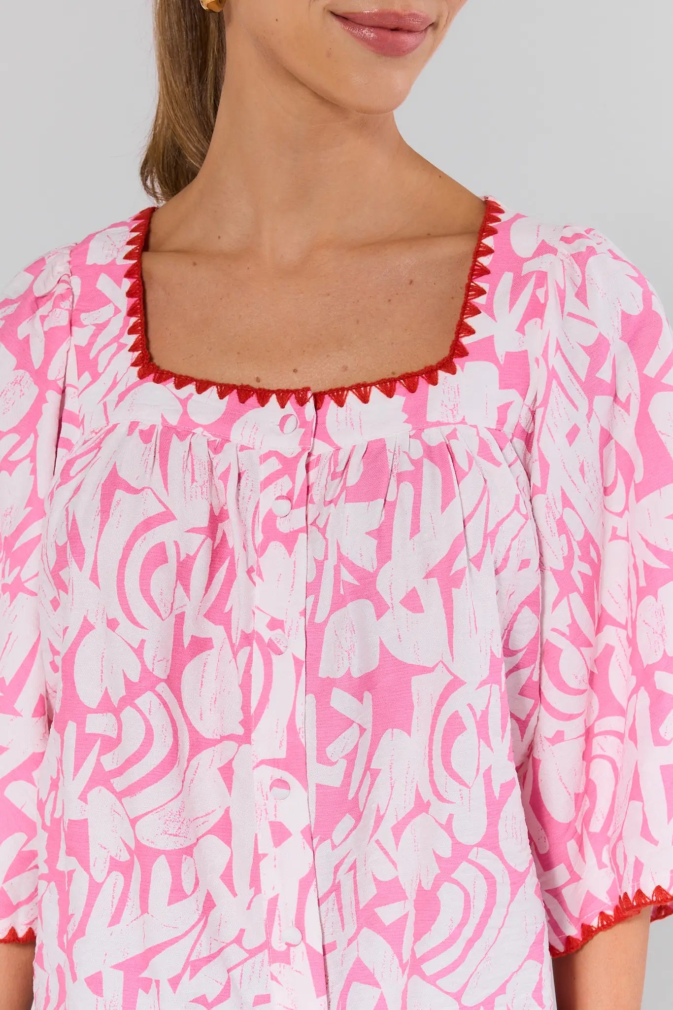 close up Pink and white patterned top with red trim on a plain background