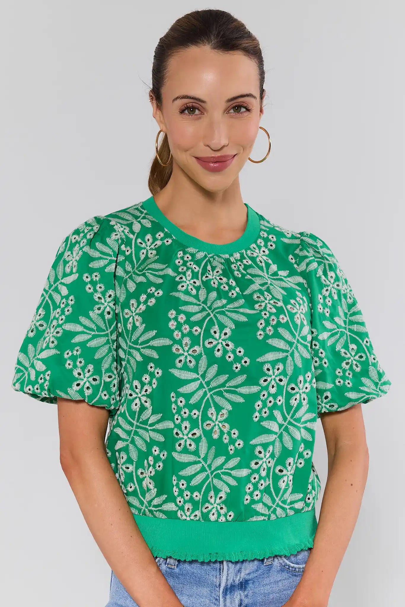 Woman wearing a green floral patterned shirt against a plain background