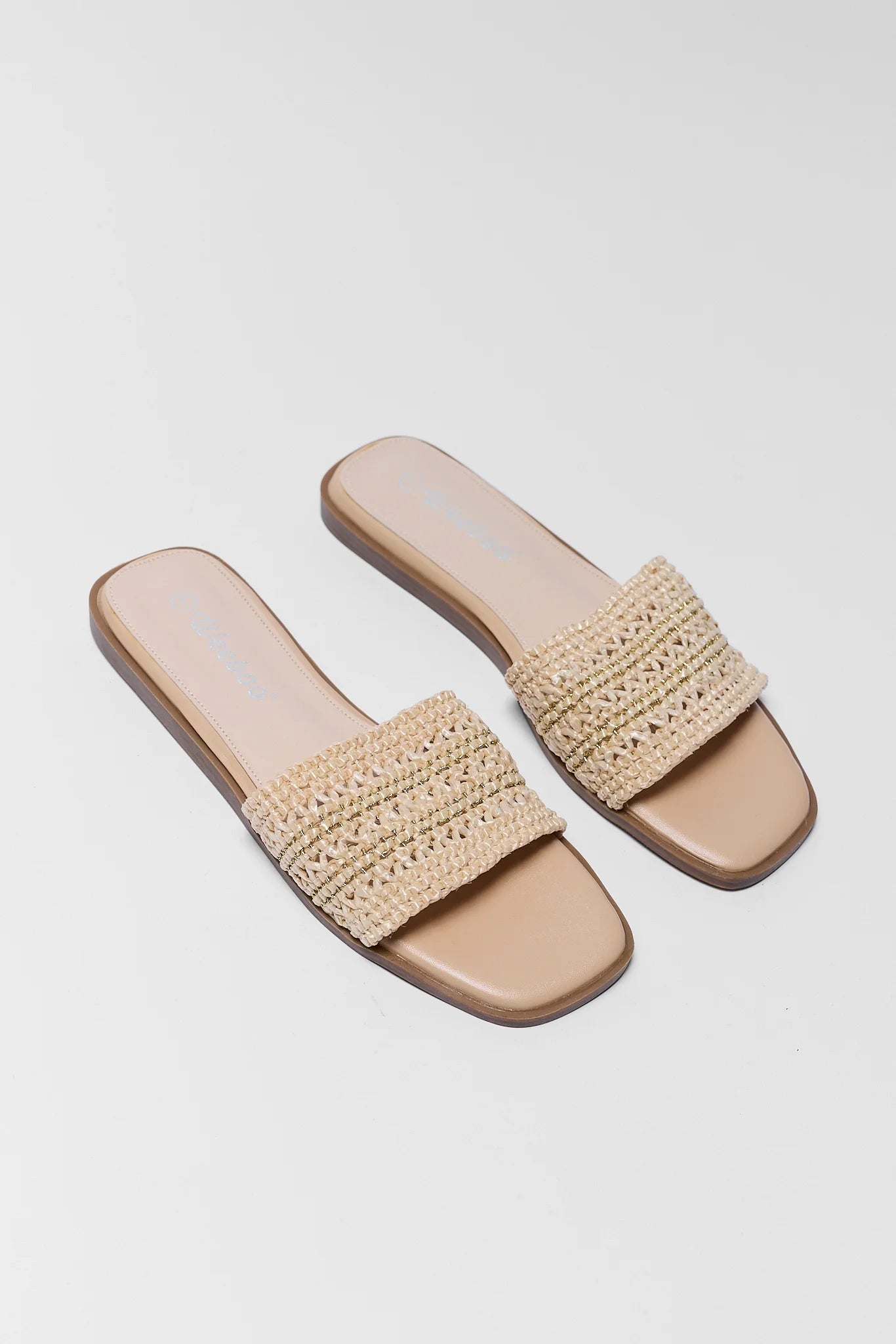 Pair of beige sandals with woven straps on a light gray background