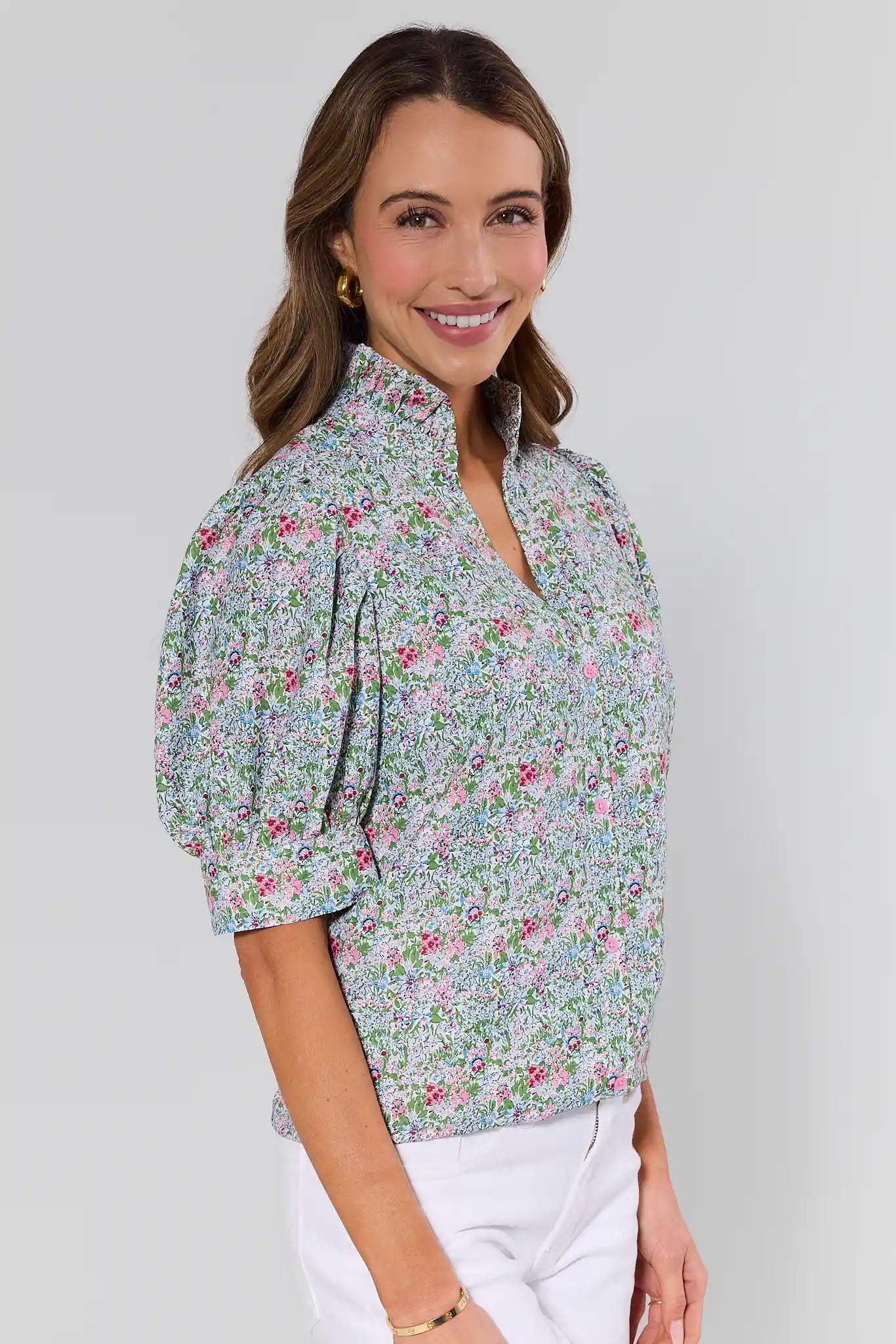 side shot Woman wearing a floral blouse against a plain background