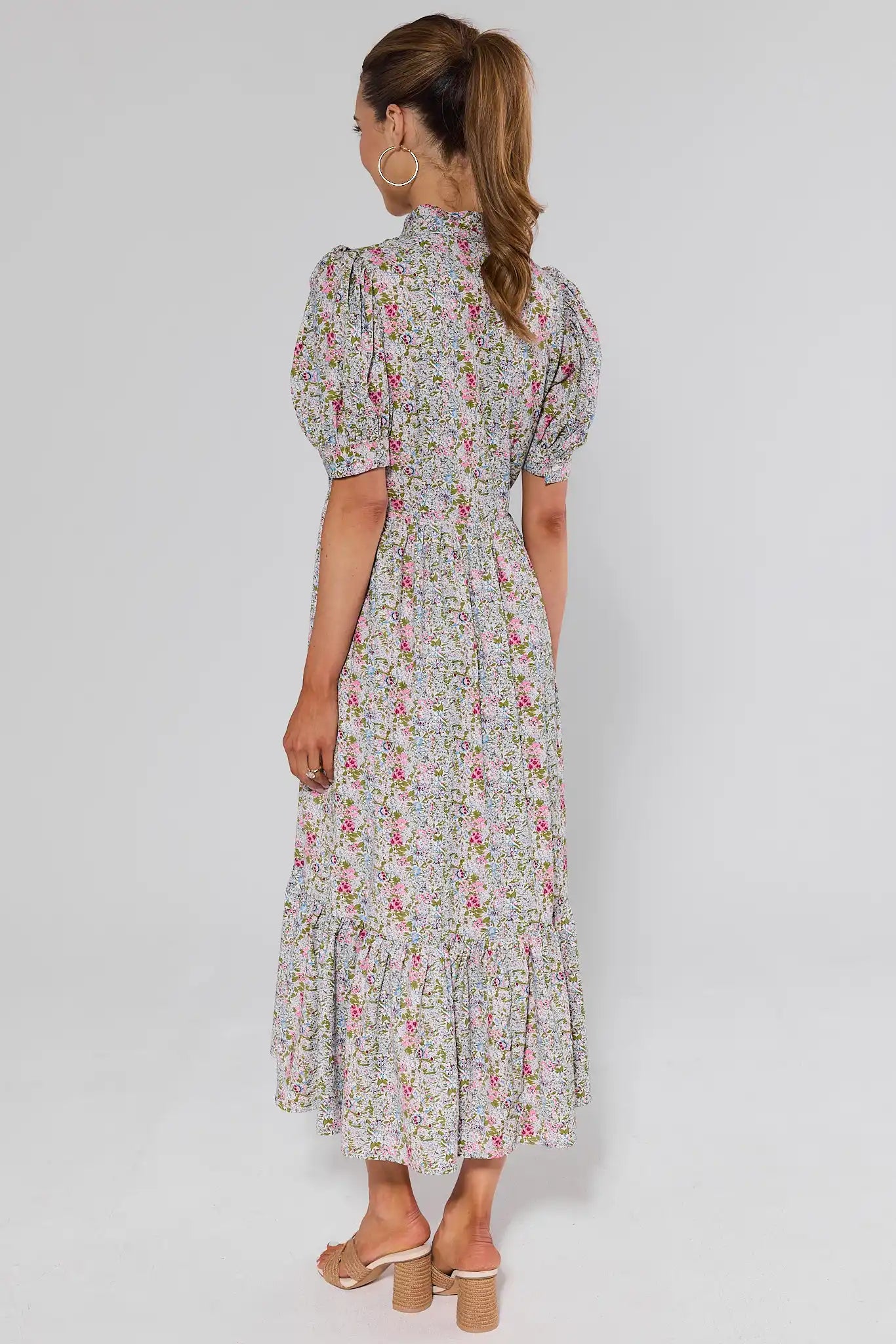 standing Woman wearing a floral dress on a plain background