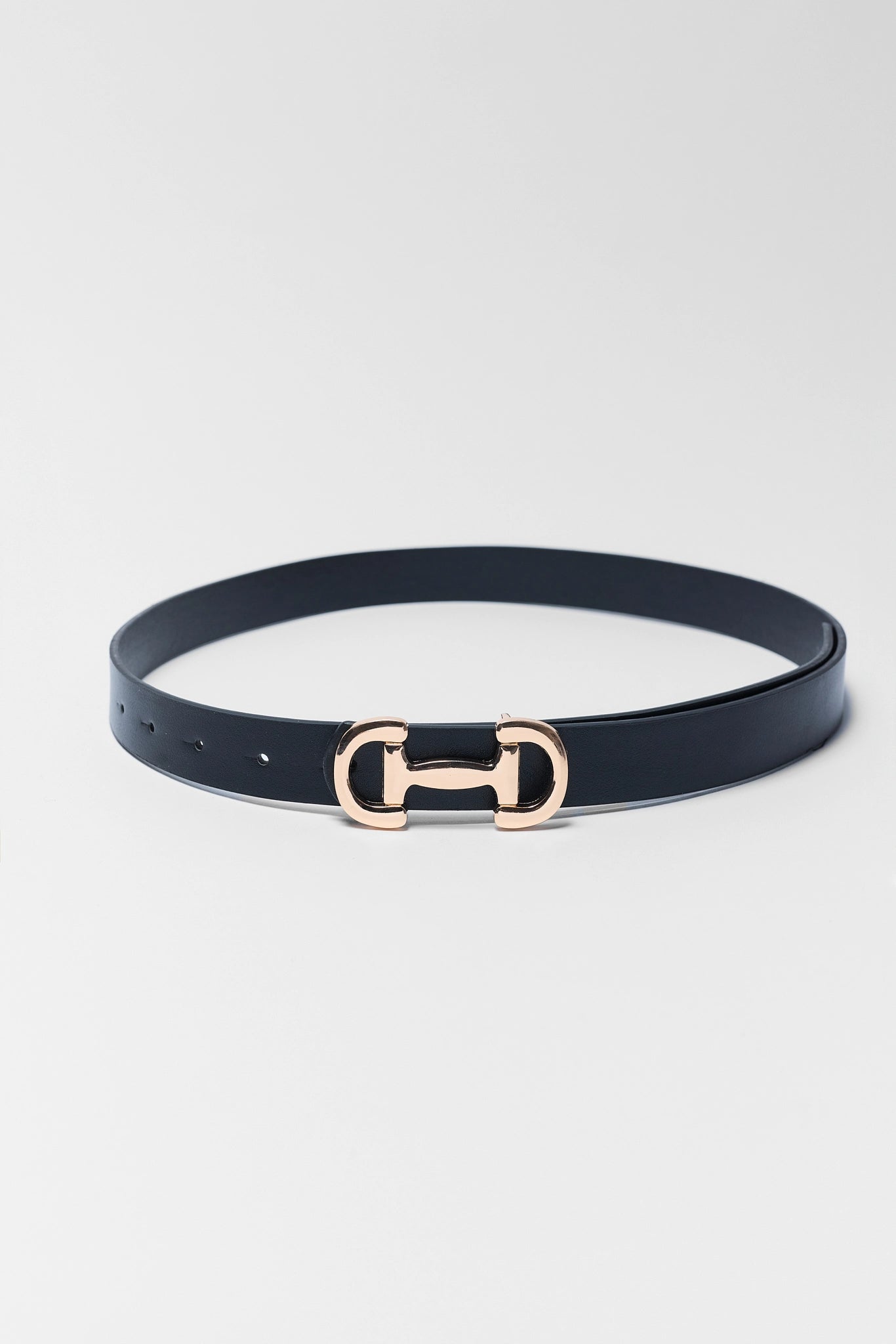 Black belt with a rose gold horsebit buckle on a light gray background