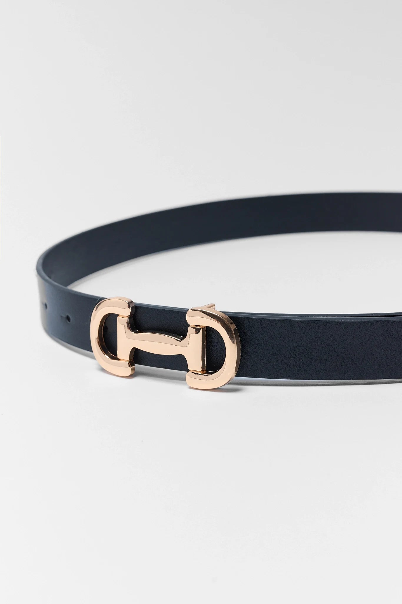 Navy belt with a rose gold buckle on a light gray background