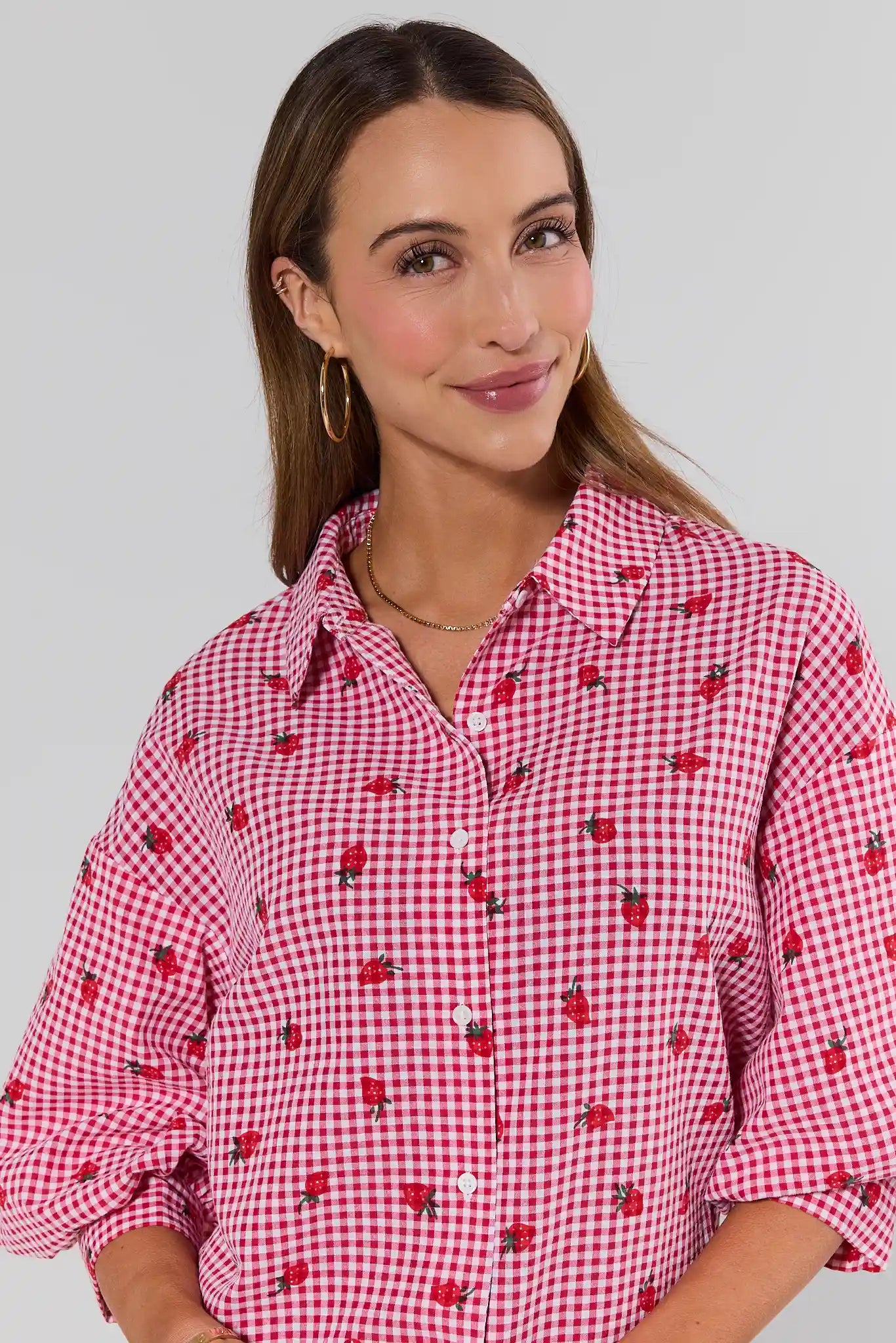 close up Woman wearing a red and white checkered shirt with a pattern of small images on a plain background