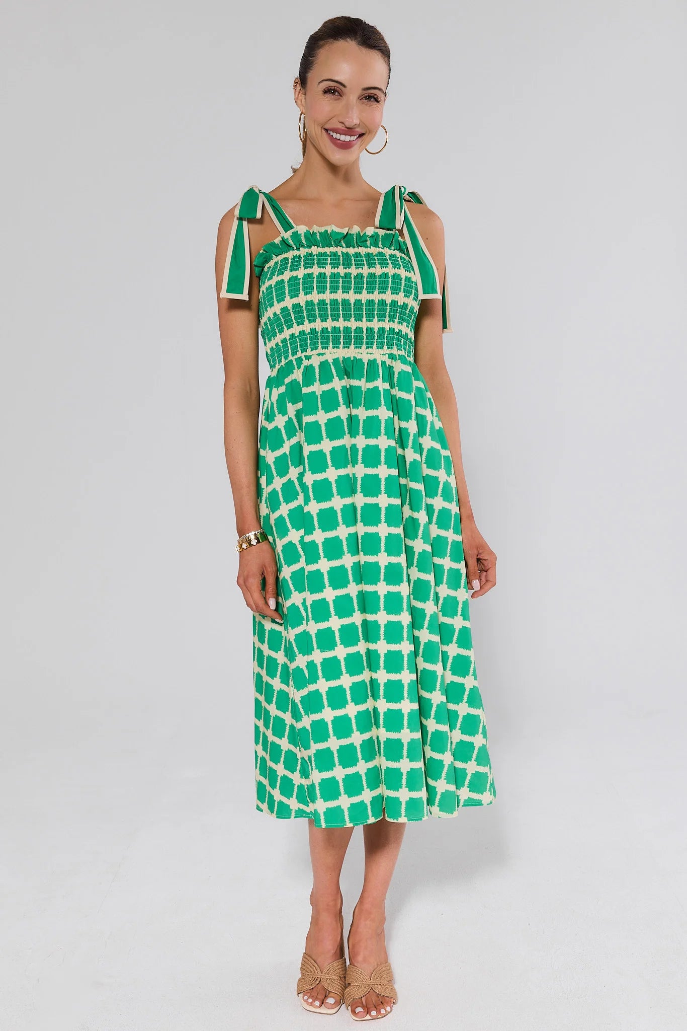 Woman wearing a green patterned dress and heels on a white background
