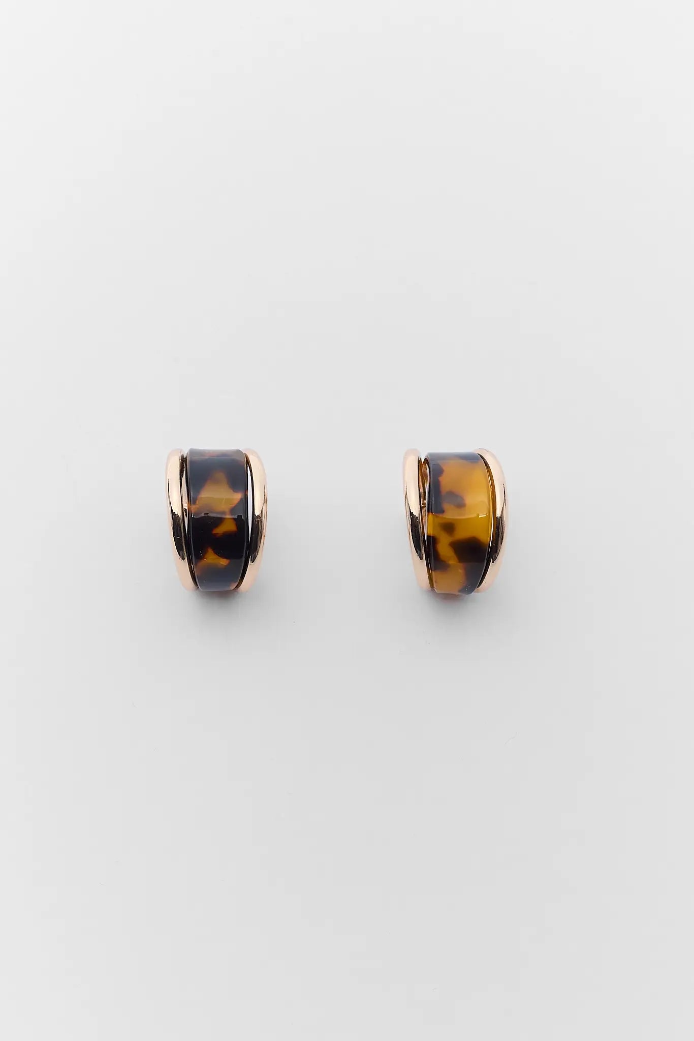 Tortoiseshell hoop earrings on a light gray background