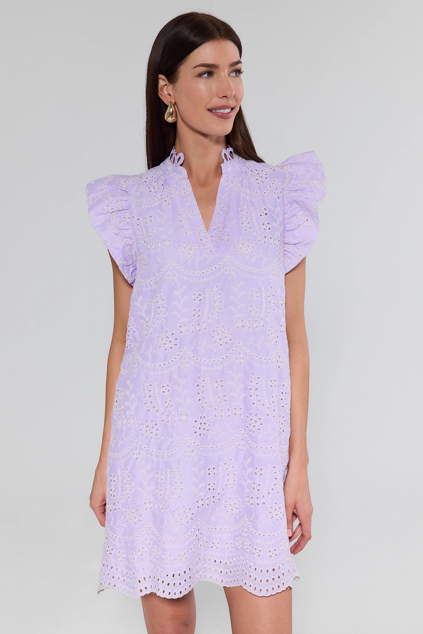 Woman wearing a light purple dress with ruffled sleeves against a plain background
