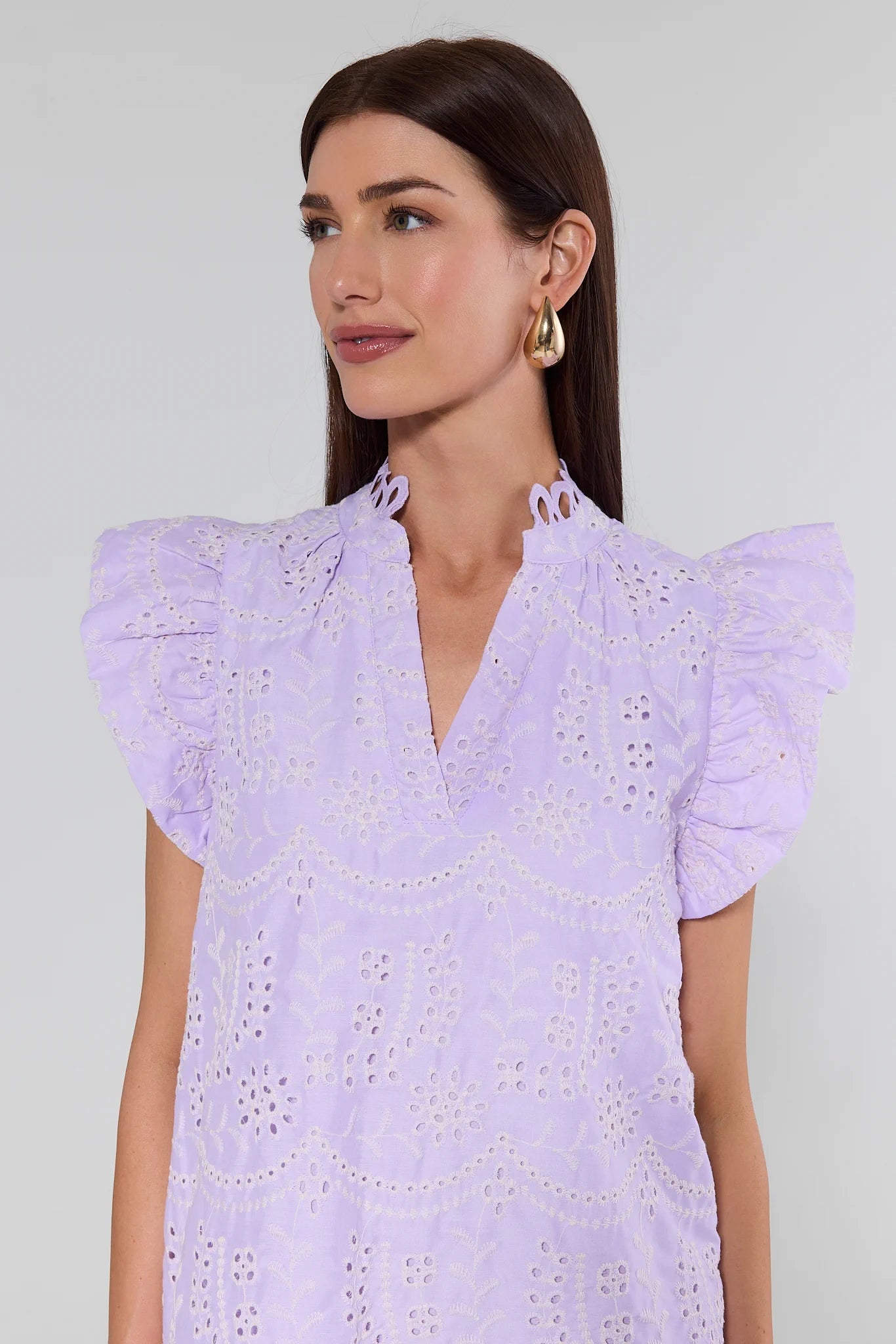 Woman wearing a light purple dress with ruffled sleeves against a plain background