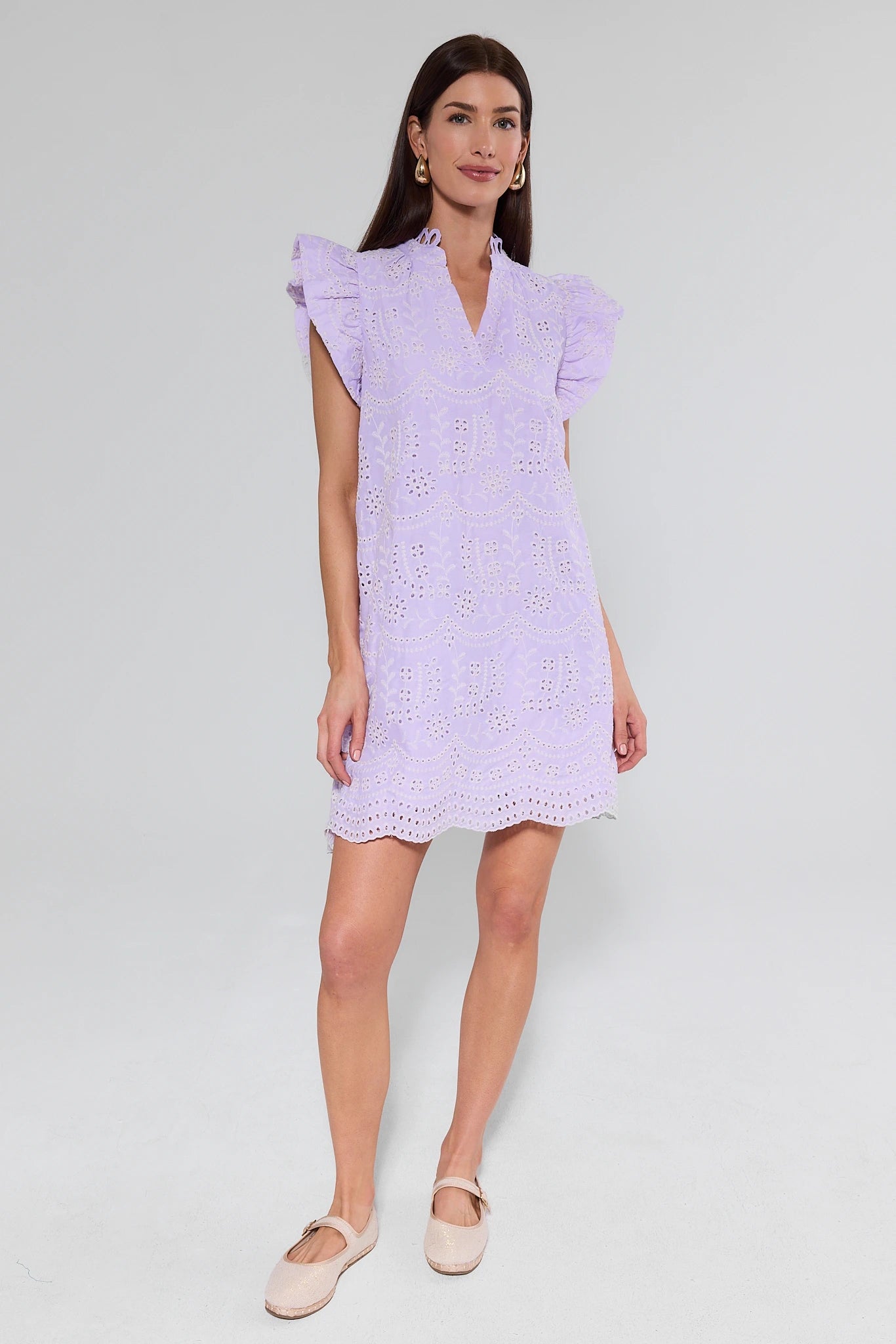 Woman wearing a light purple dress with lace details on a white background