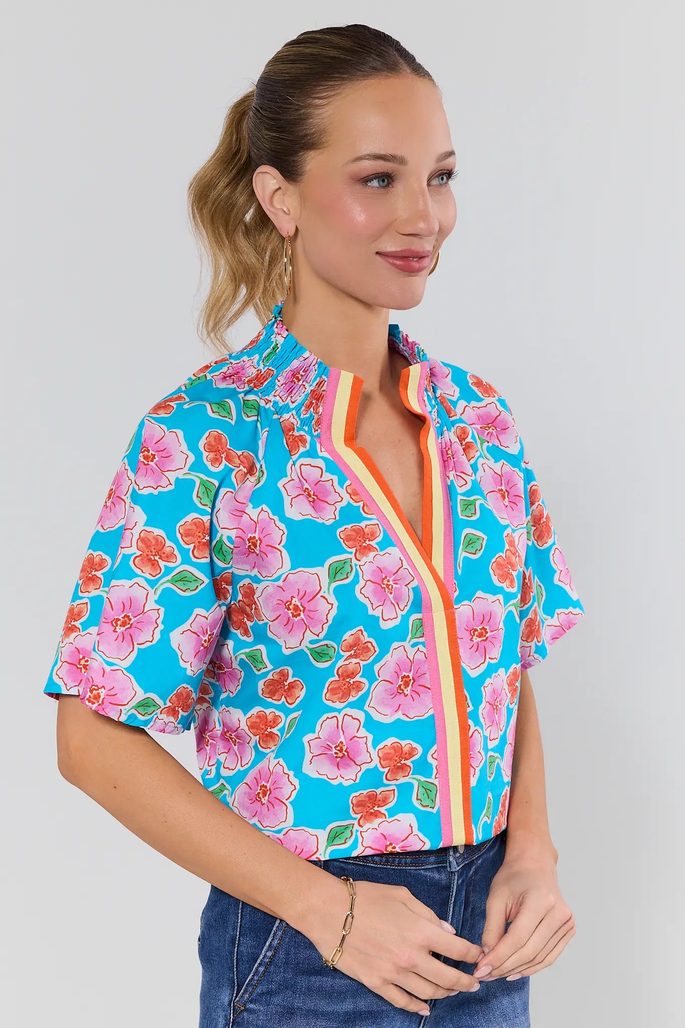 Woman wearing a colorful floral shirt and jeans with a white background