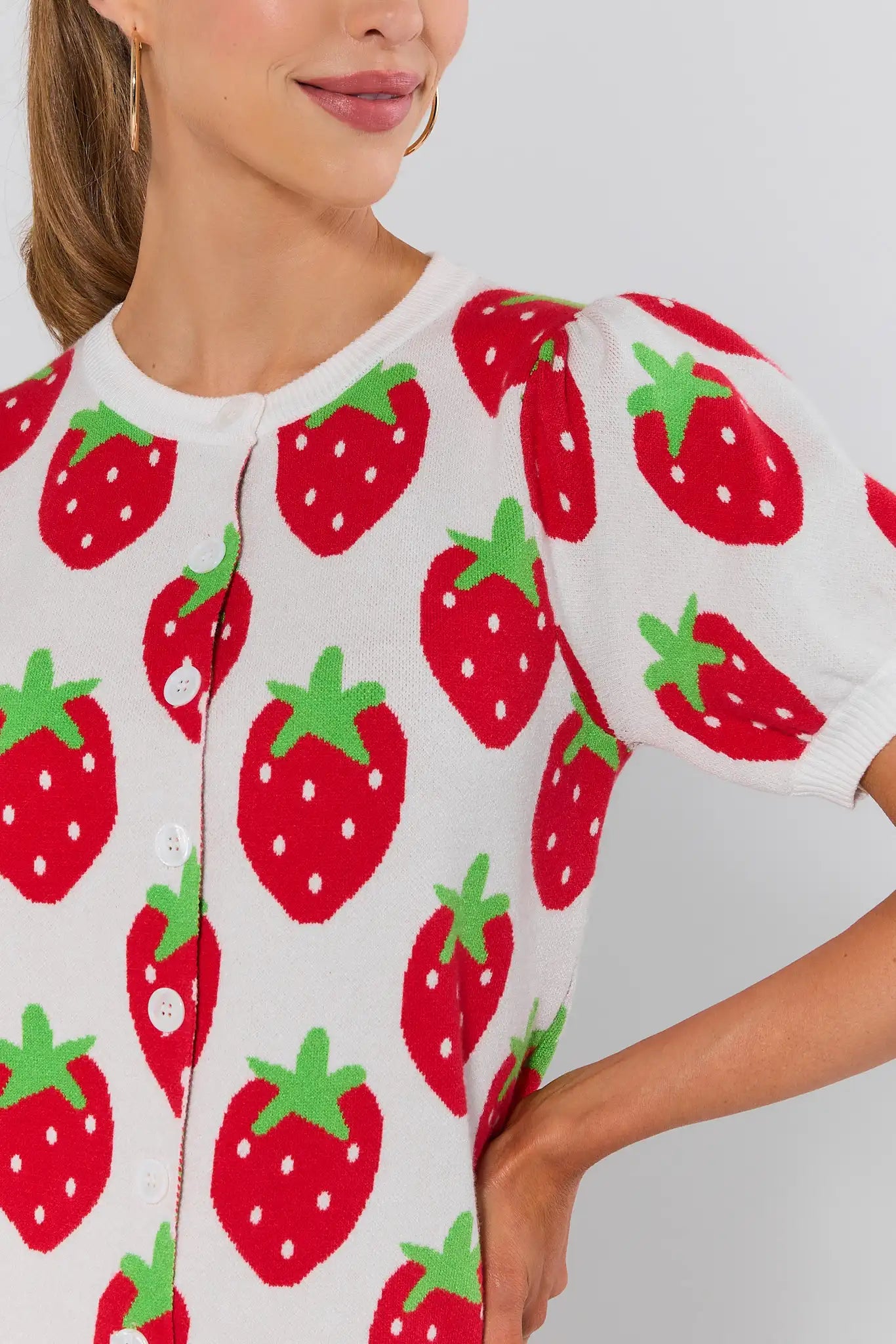 close up Woman wearing a white sweater with red strawberry pattern on a light gray background