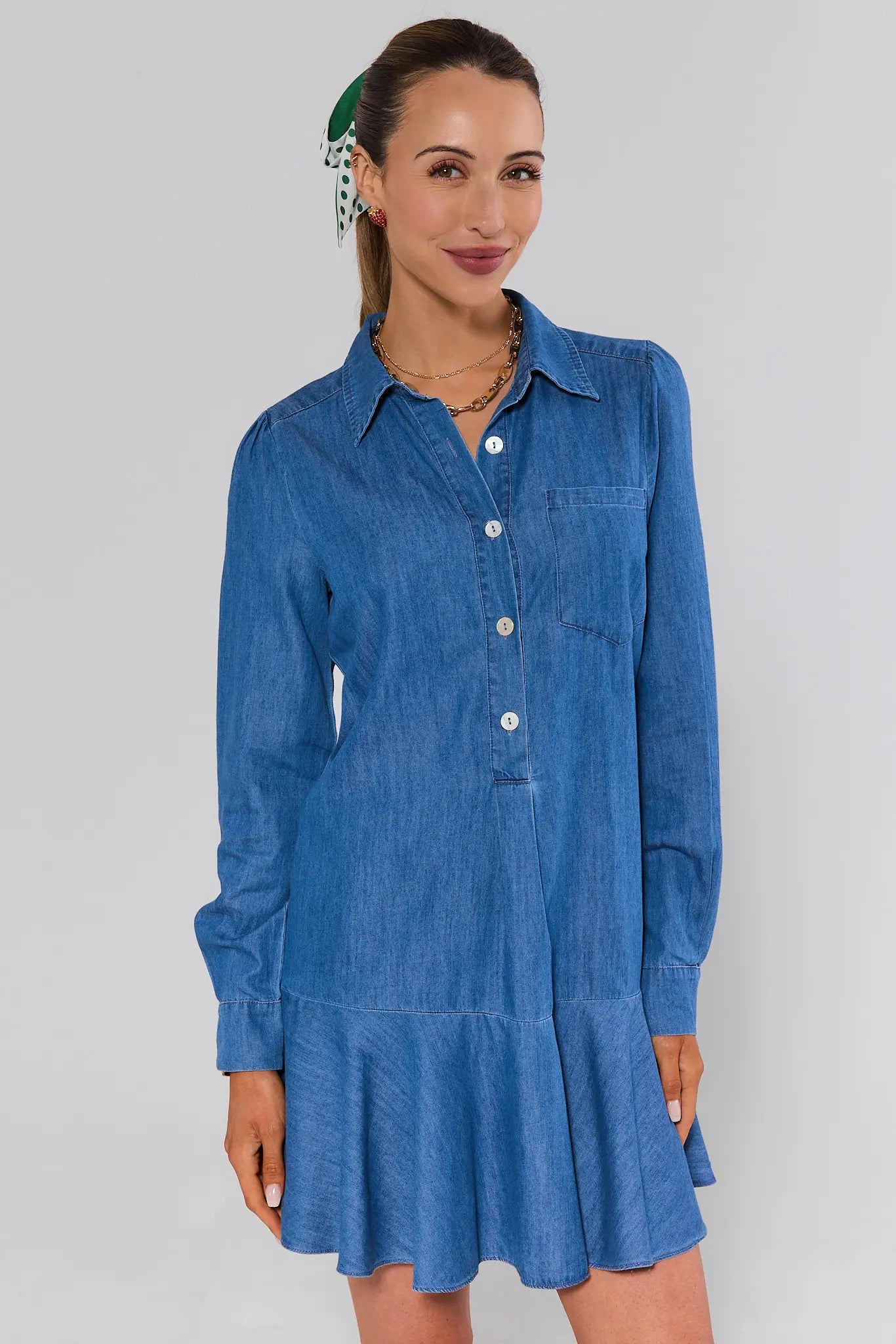 Woman wearing a blue denim dress against a plain background