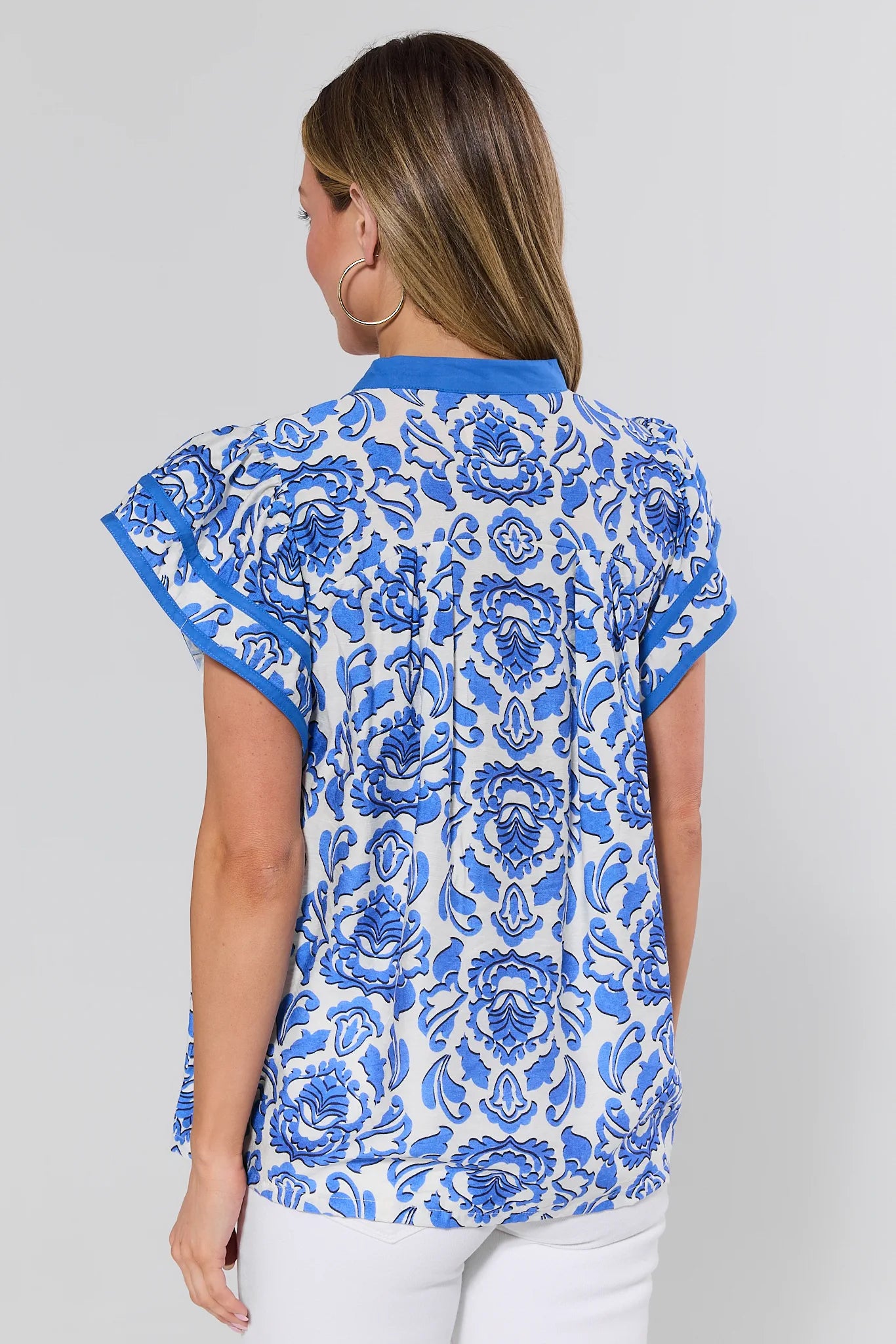 Woman wearing a blue floral patterned shirt on a gray background