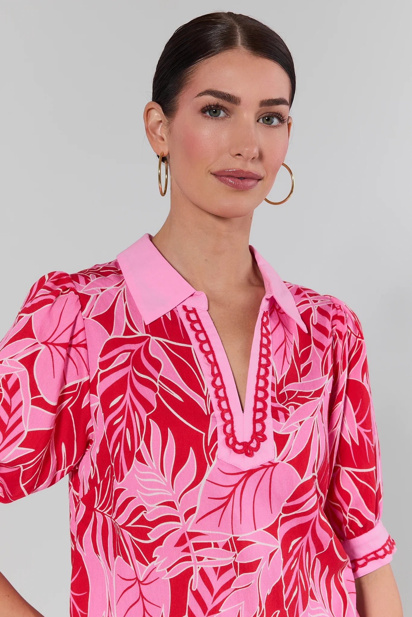 Woman wearing a pink and red patterned dress against a plain background
