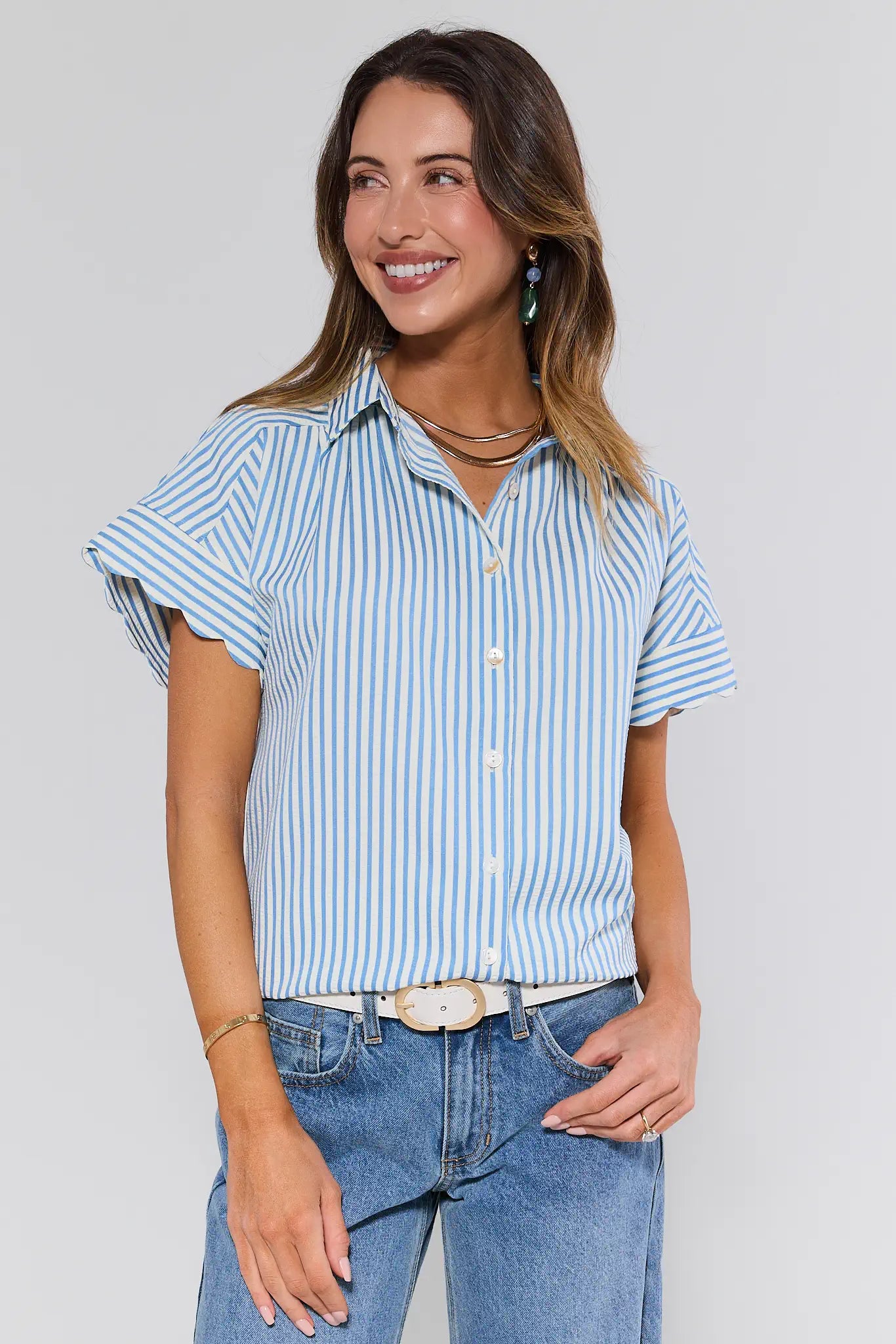 Woman wearing a blue and white striped shirt and jeans against a plain background