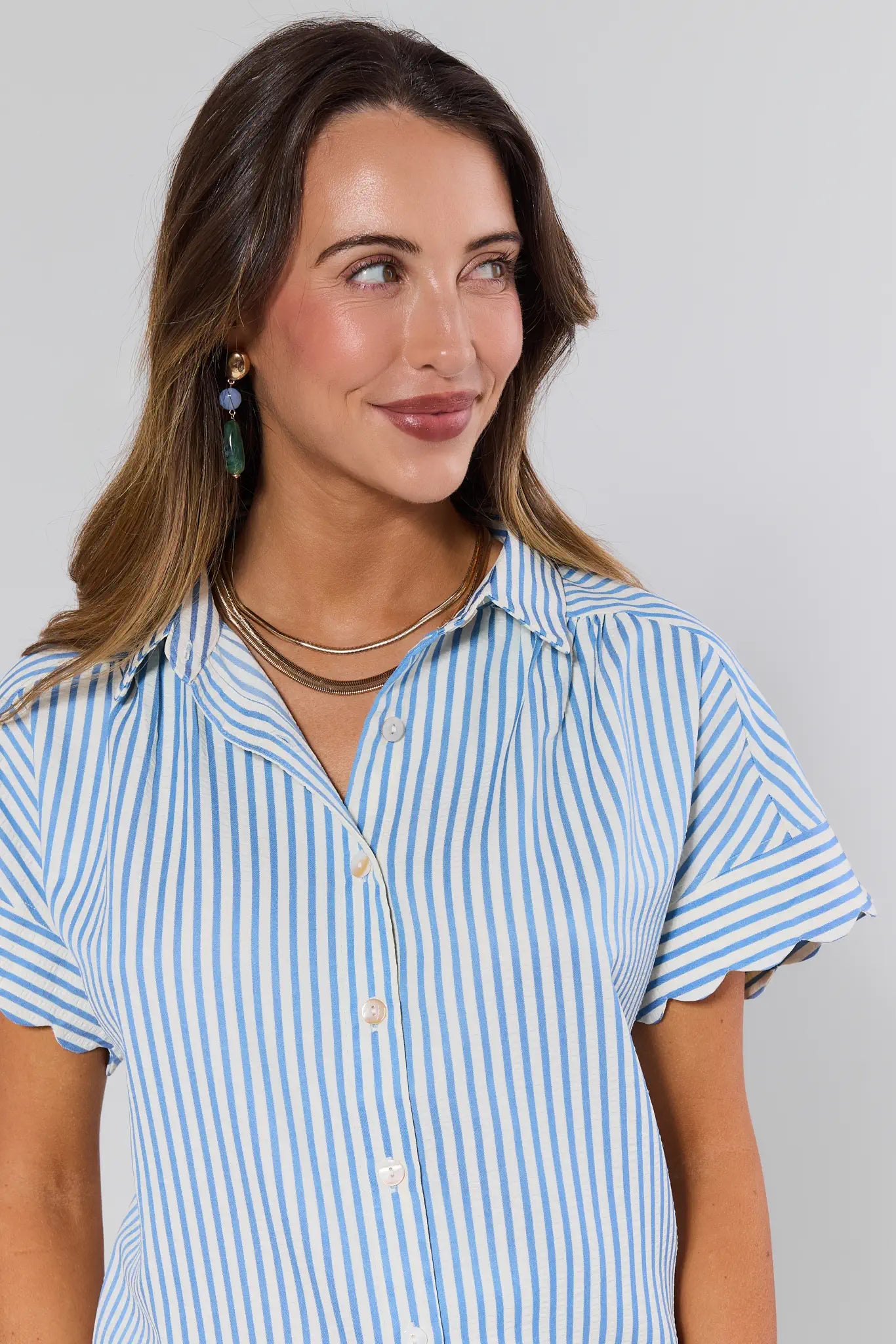 Woman wearing a blue and white striped shirt against a gray background