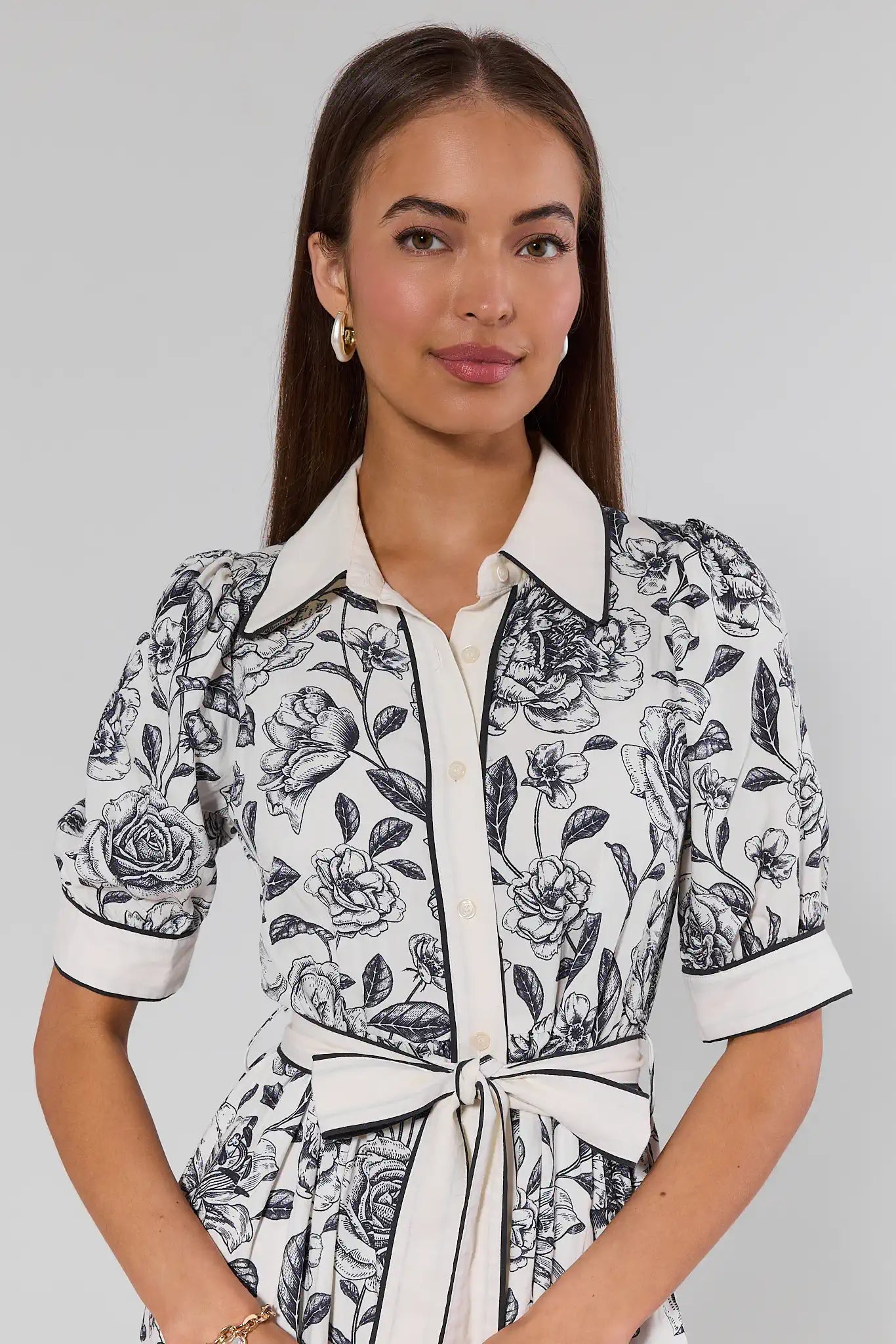 Woman wearing a black and white floral patterned dress against a gray background