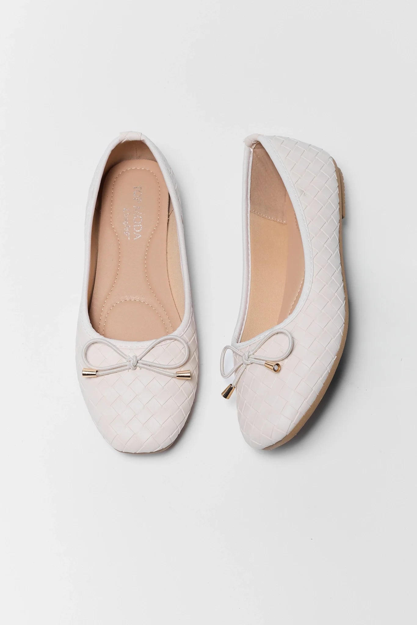 Pair of white flats with bow details on a light gray background