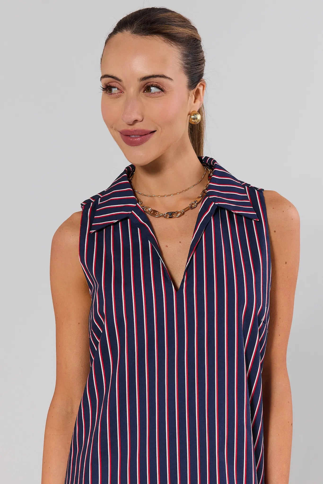 close up Woman wearing a sleeveless striped dress with a plain background