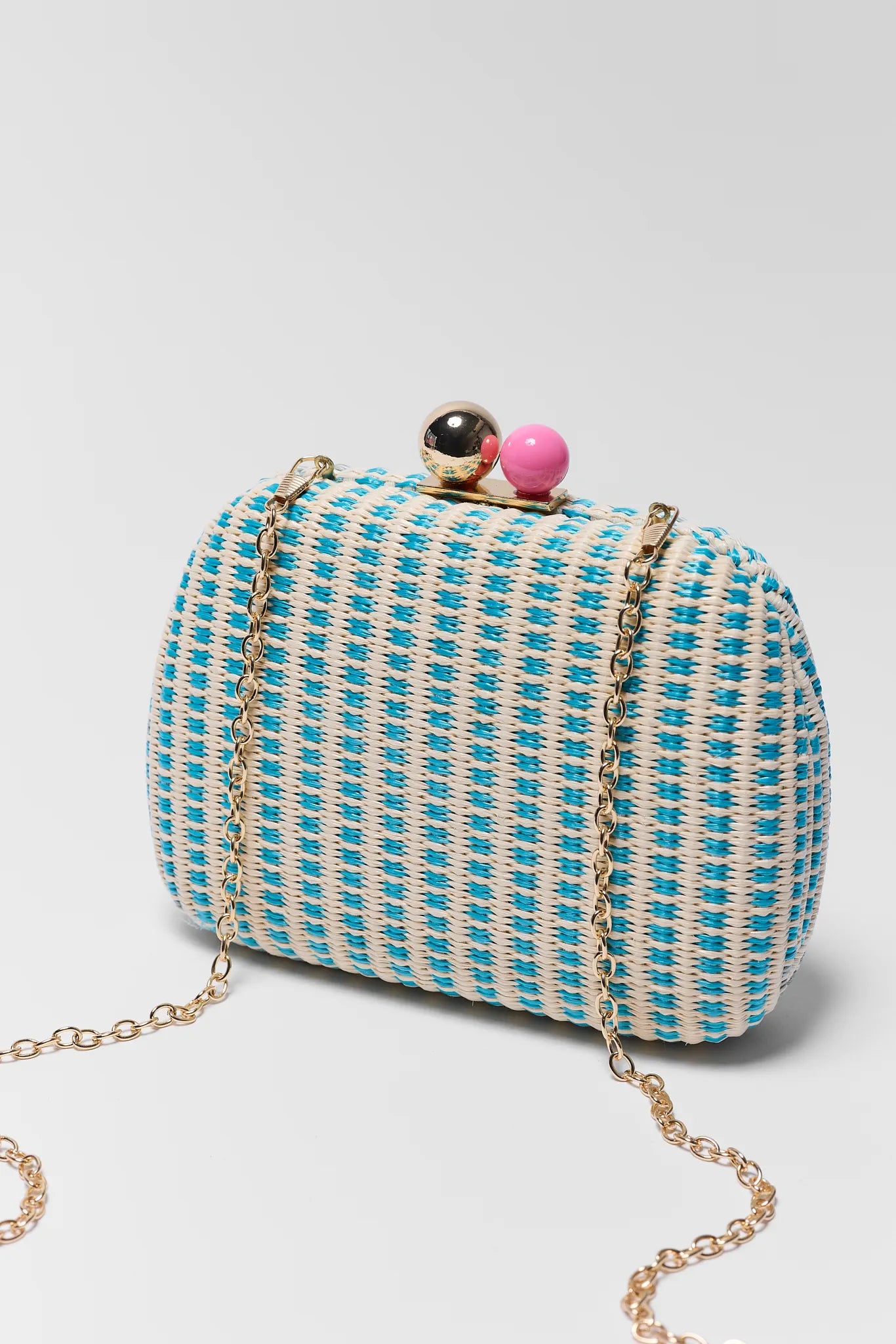 Blue and white patterned clutch bag with a chain strap on a light gray background