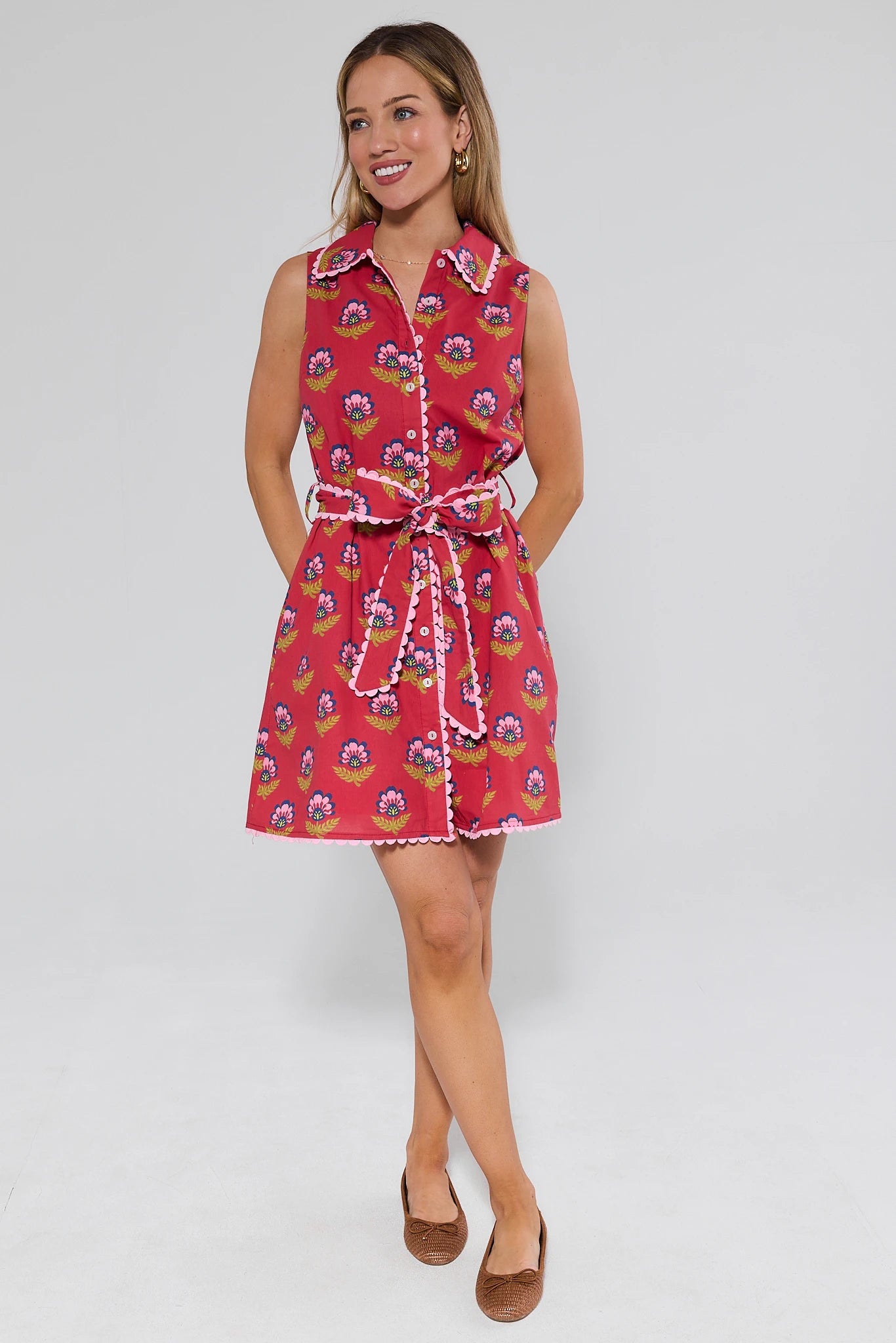 Woman wearing a red floral dress with a belt on a white background