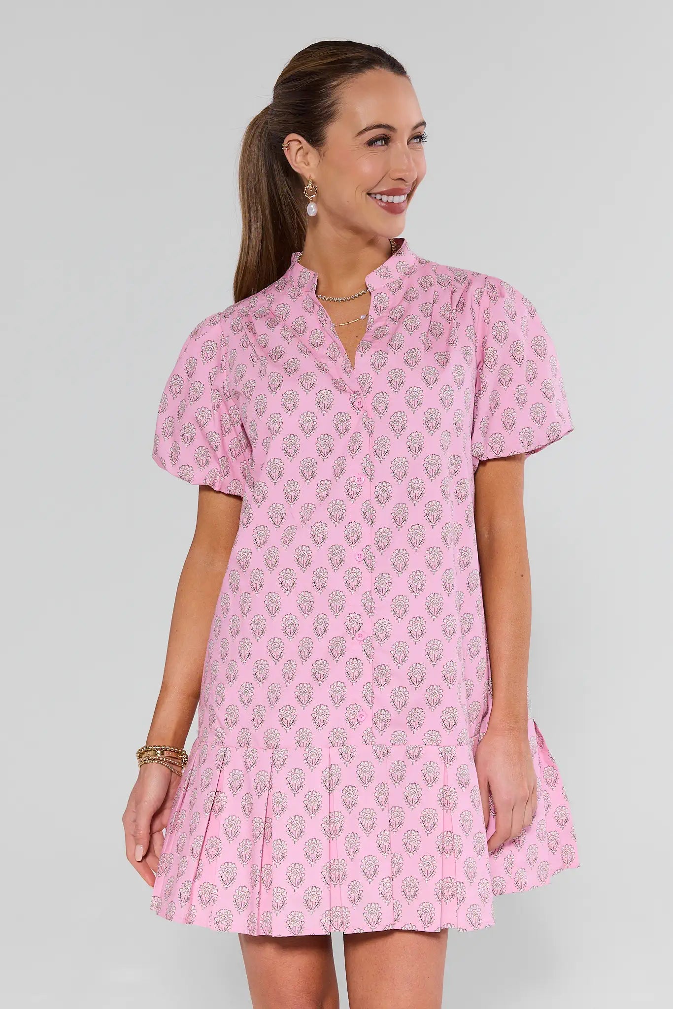 Woman wearing a pink patterned dress against a gray background