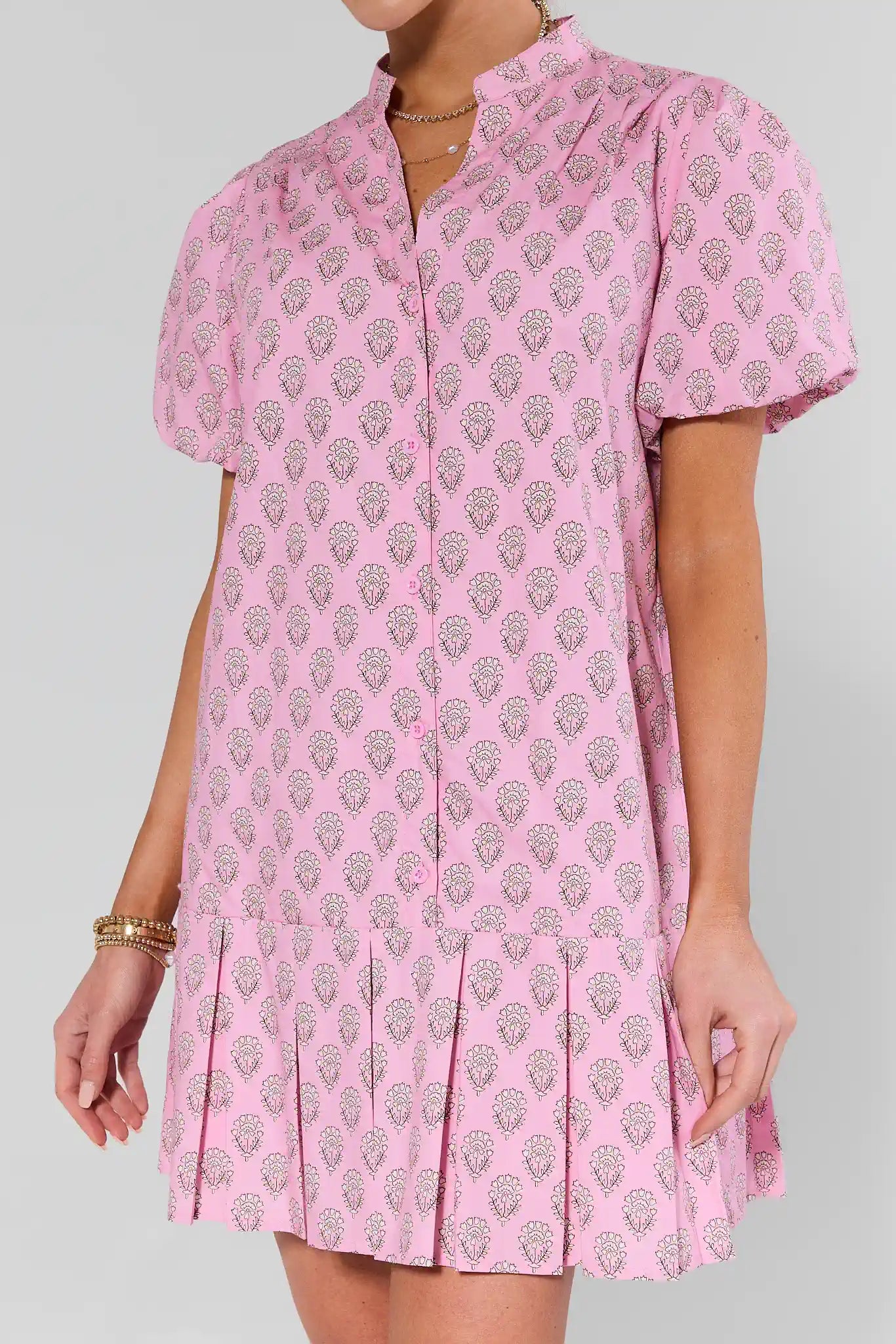 Pink patterned dress worn by a person on a gray background