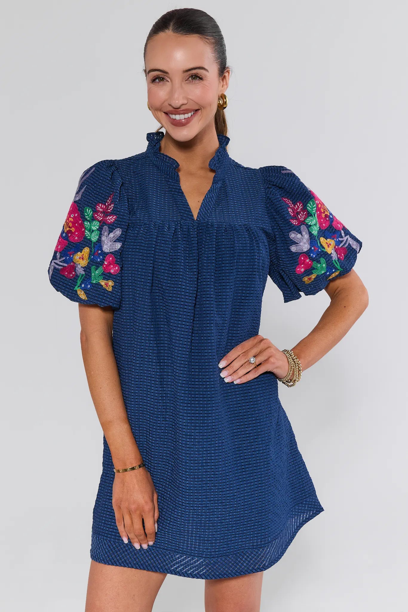 Woman wearing a blue dress with colorful floral embroidery on a white background