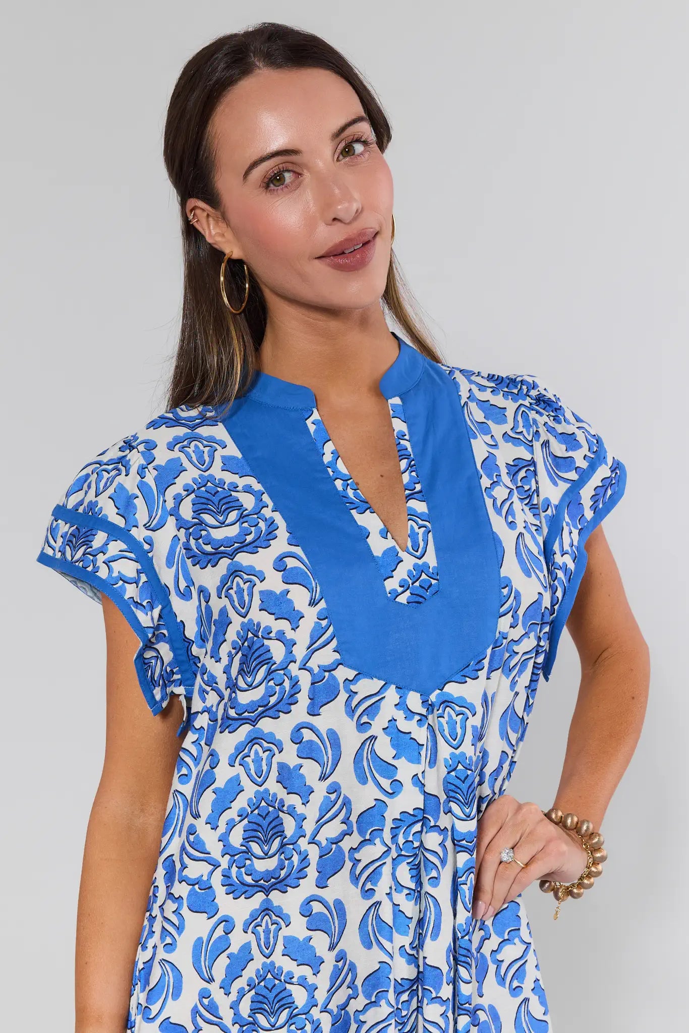 Woman wearing a blue and white patterned dress against a gray background