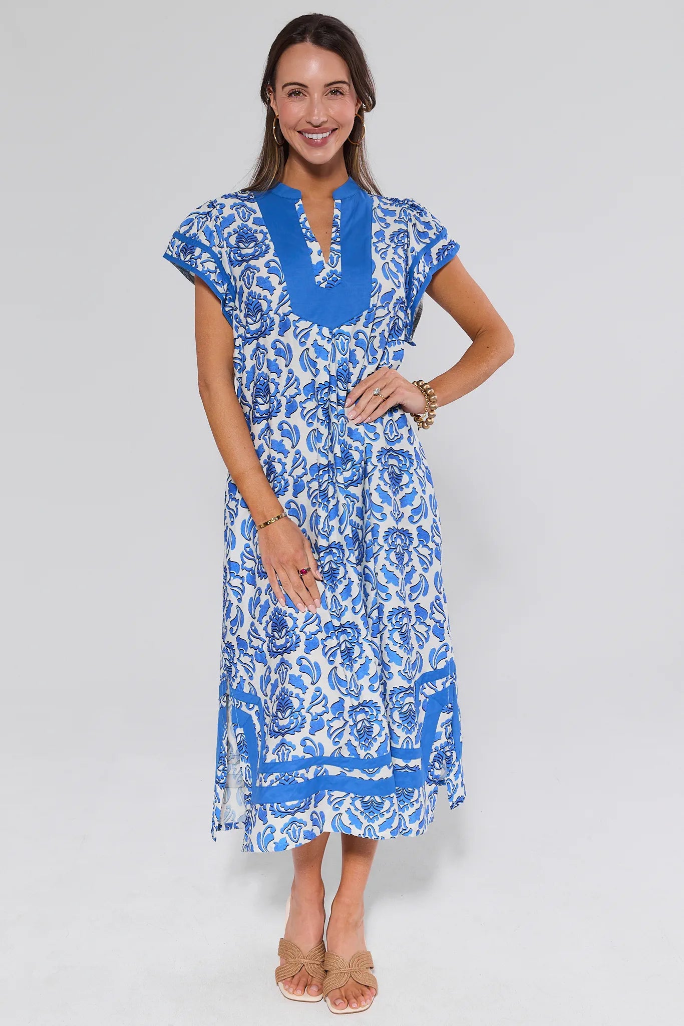 Woman wearing a blue and white floral dress on a gray background