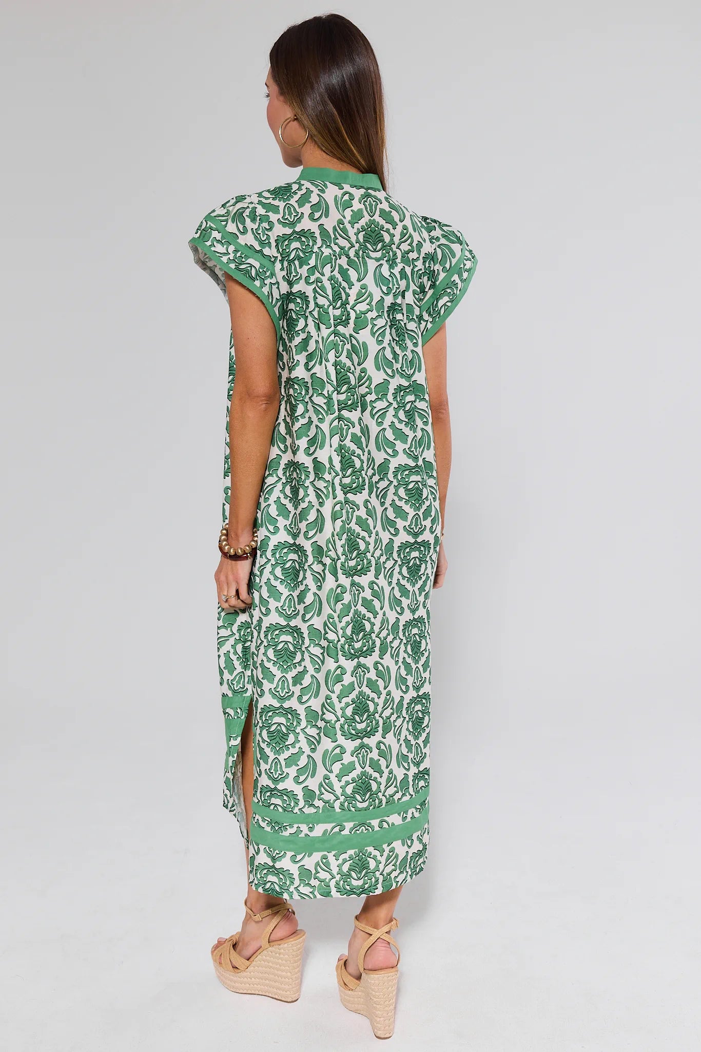 Woman wearing a green and white patterned dress on a plain background