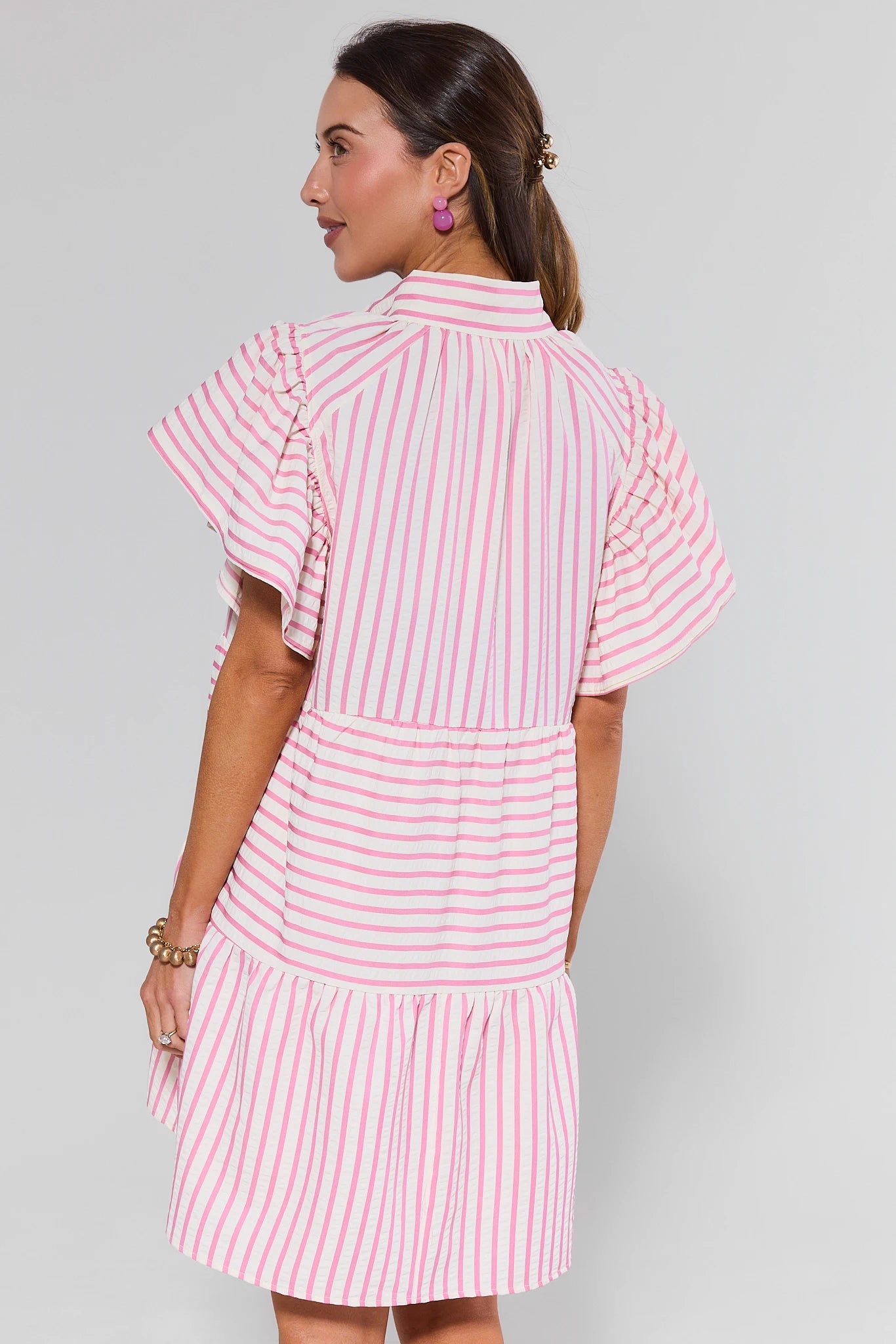 Woman wearing a pink and white striped dress against a gray background