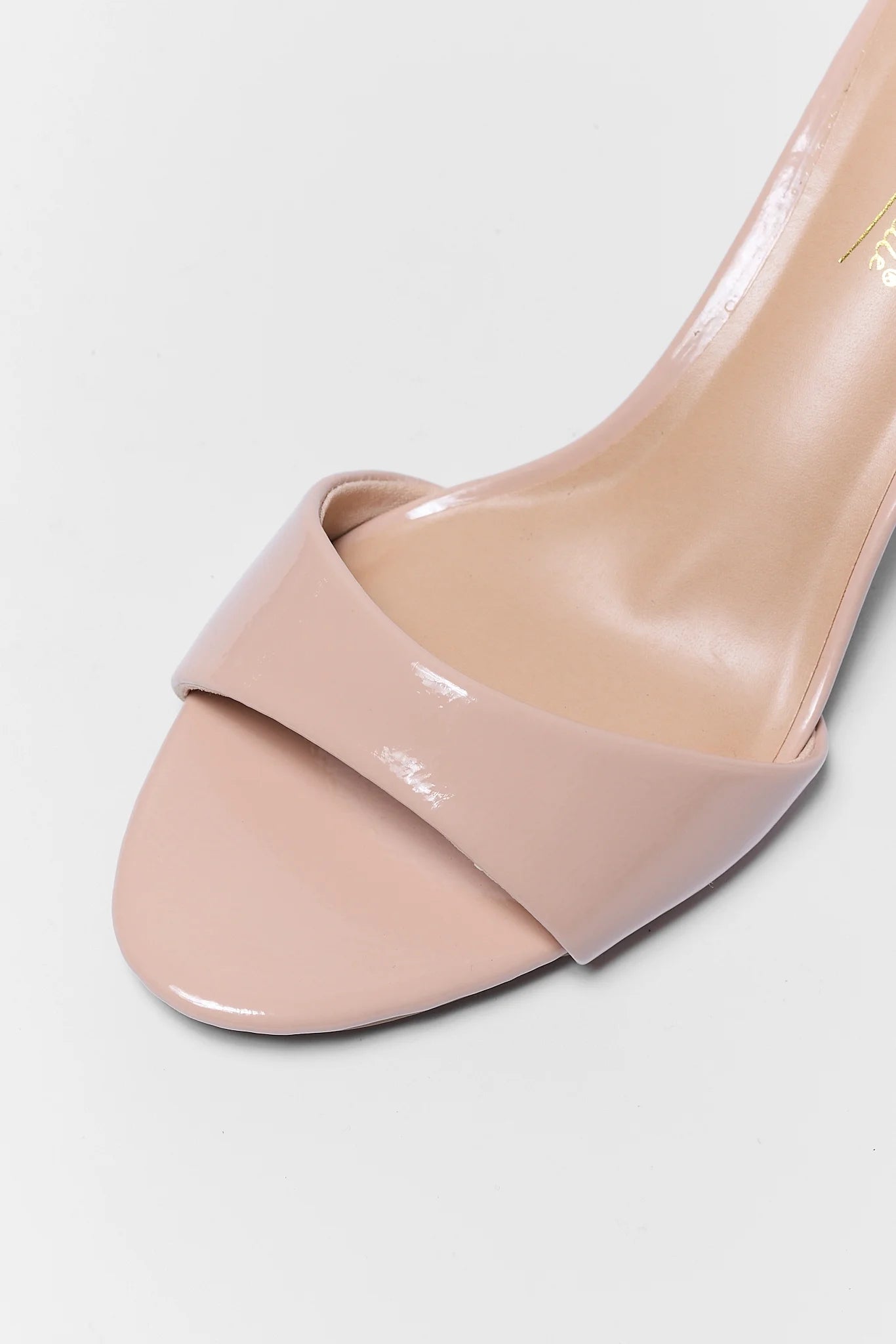 Beige high-heeled shoe on a light gray background close up