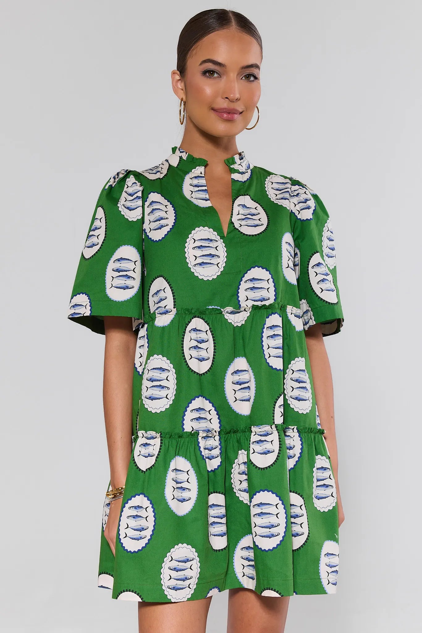 Woman wearing a green dress with white and blue pattern on a plain background