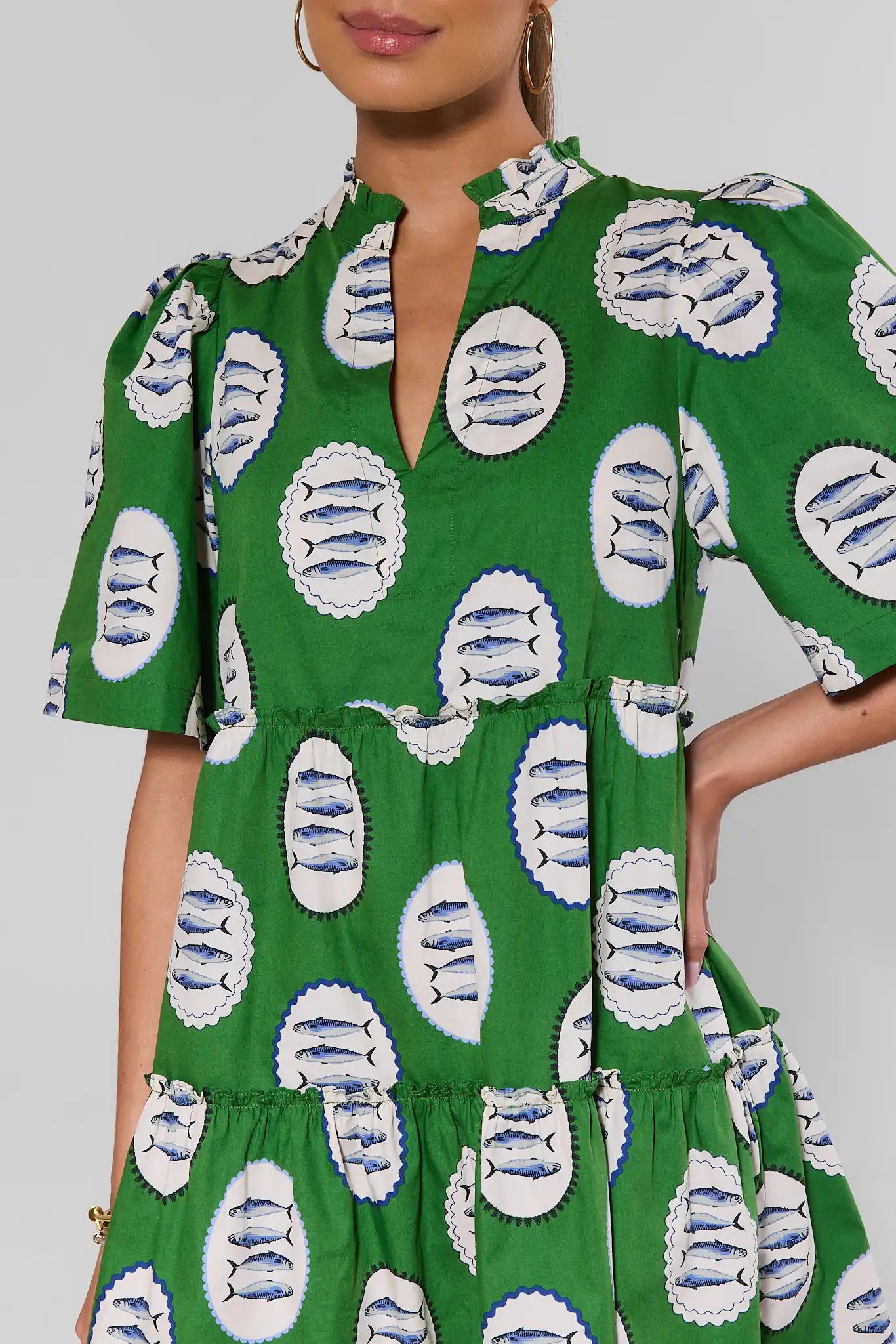 close up Green dress with white and blue fish pattern worn by a model on a gray background