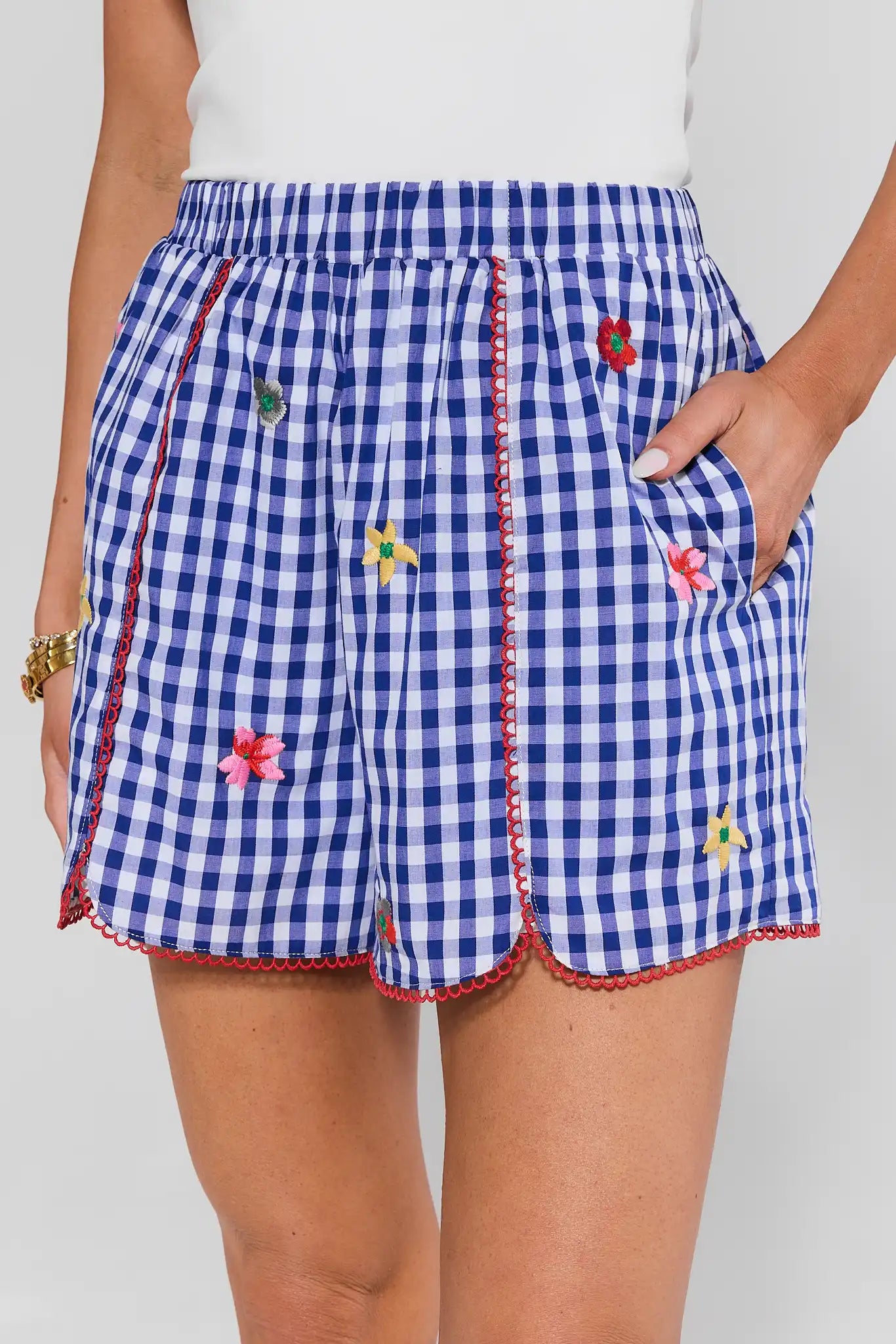 Blue and white checkered shorts with floral embroidery on a plain background