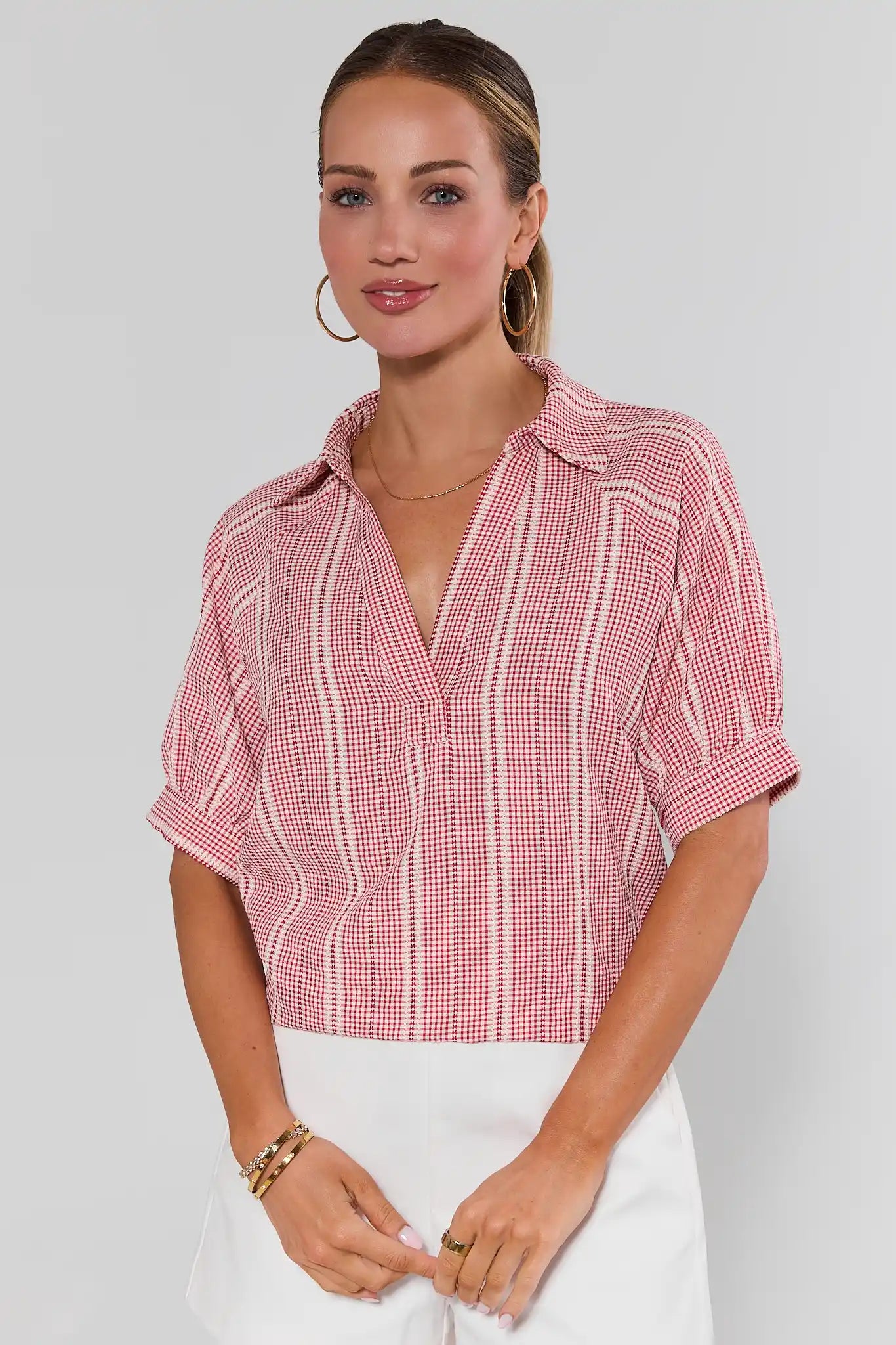 Woman wearing a red and white checkered blouse against a plain background
