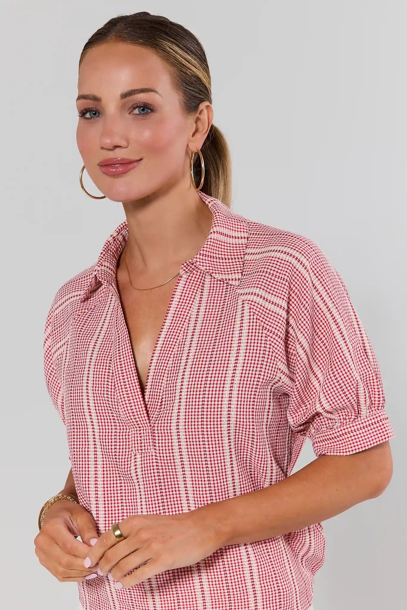 close up Woman wearing a red and white checkered dress against a plain background