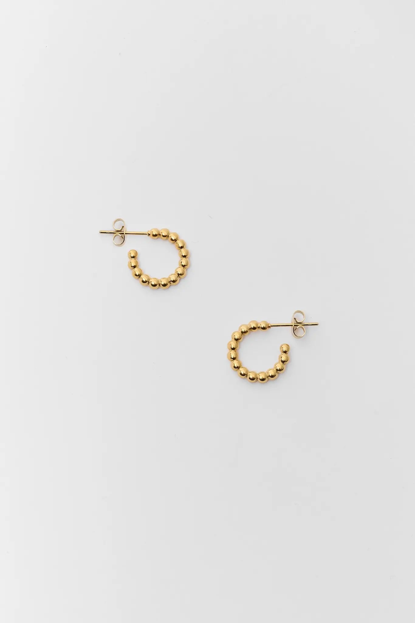 Pair of gold hoop earrings on a light gray background
