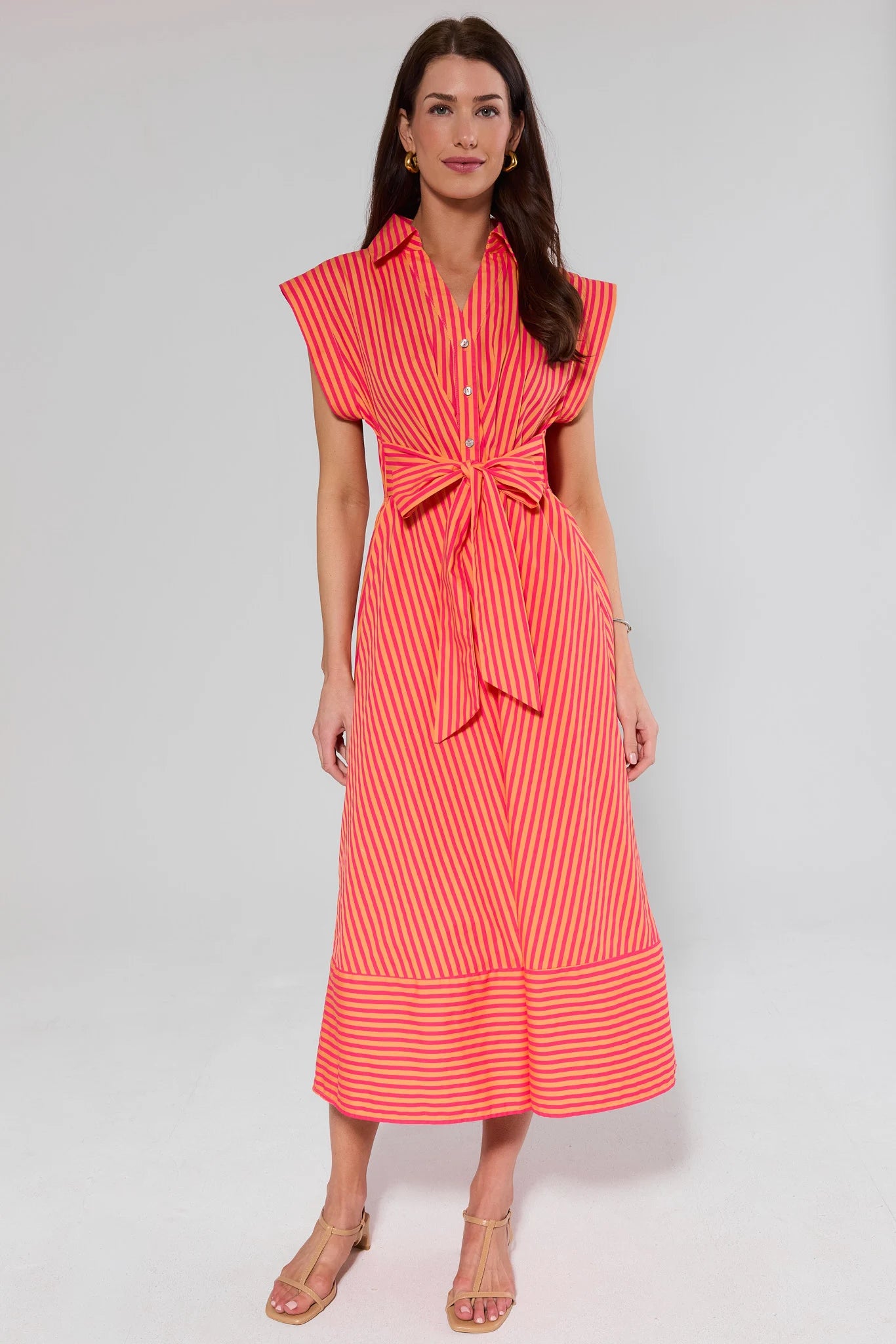 Woman wearing a red and orange striped dress on a gray background