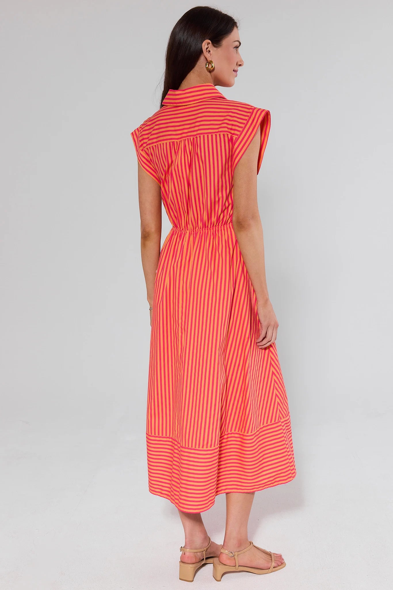 Woman standing wearing a red and white striped dress on a plain background