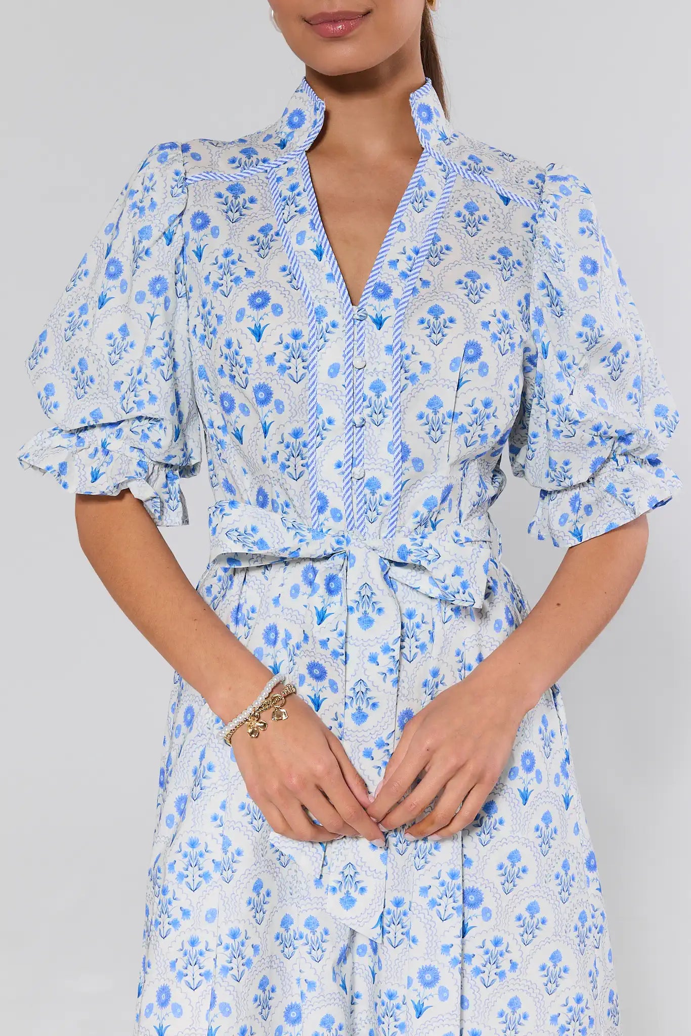 Woman wearing a blue floral dress against a gray background