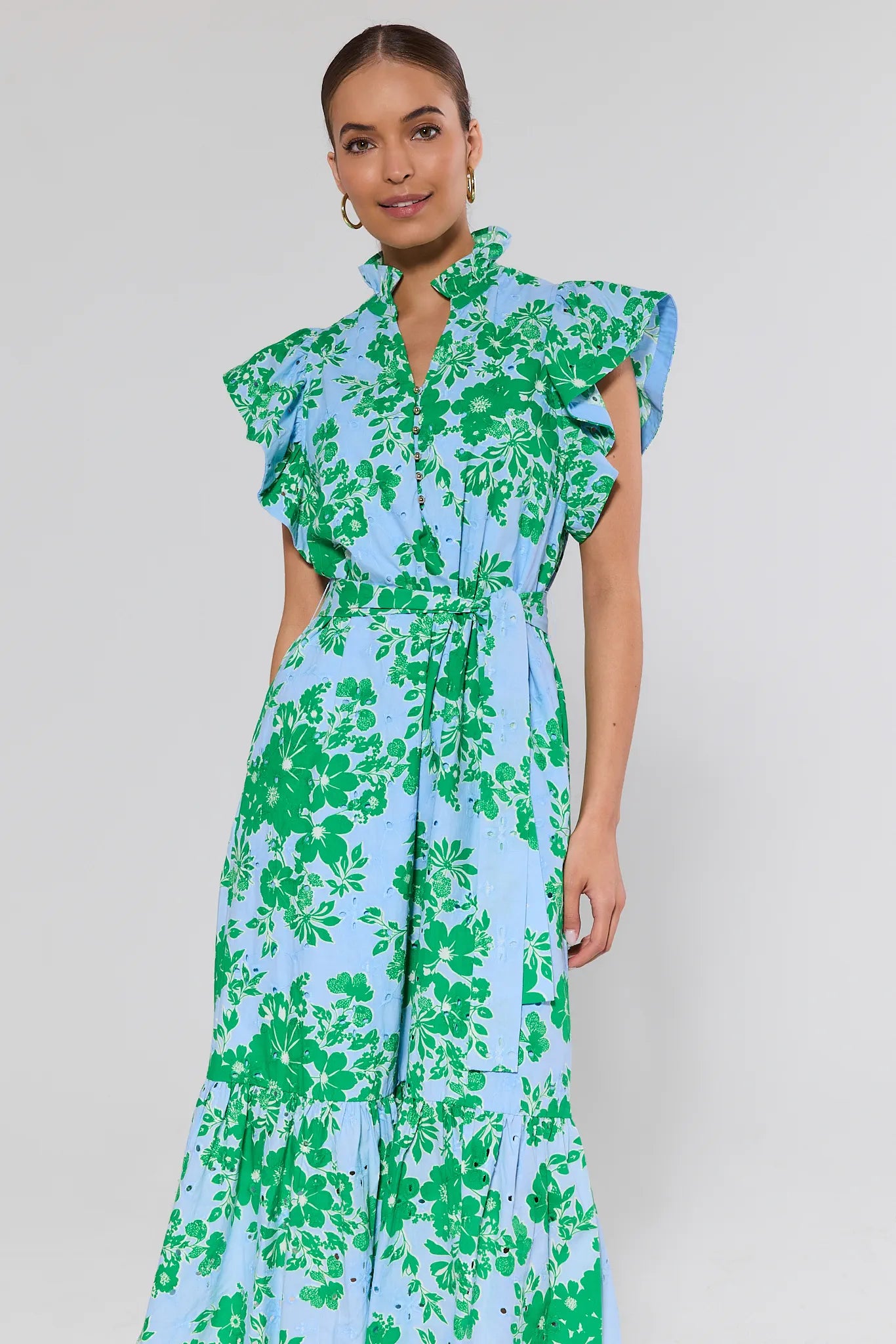 Woman wearing a floral dress with green and blue pattern on a plain background