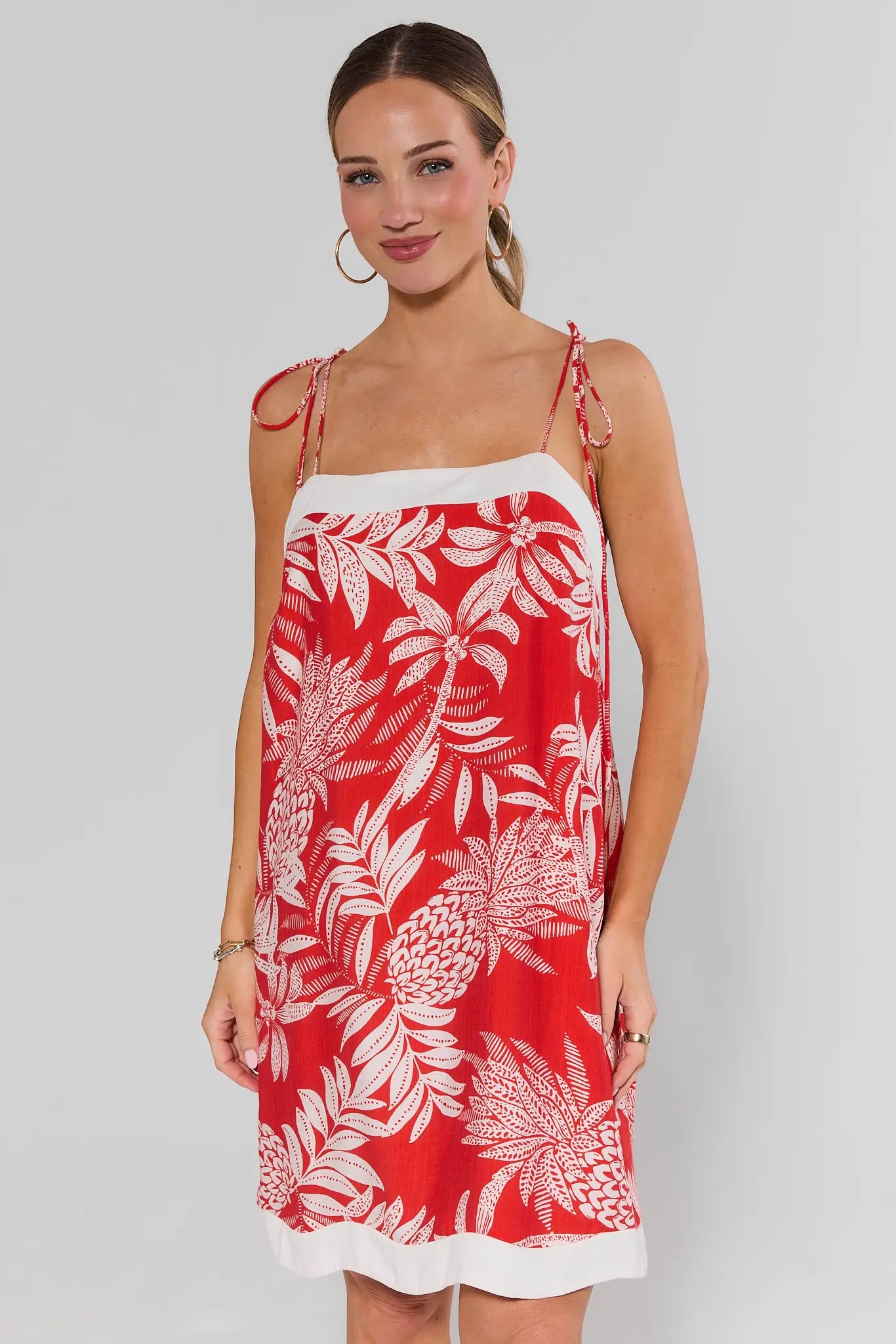 Woman wearing a red libby dress with white floral pattern on a plain background