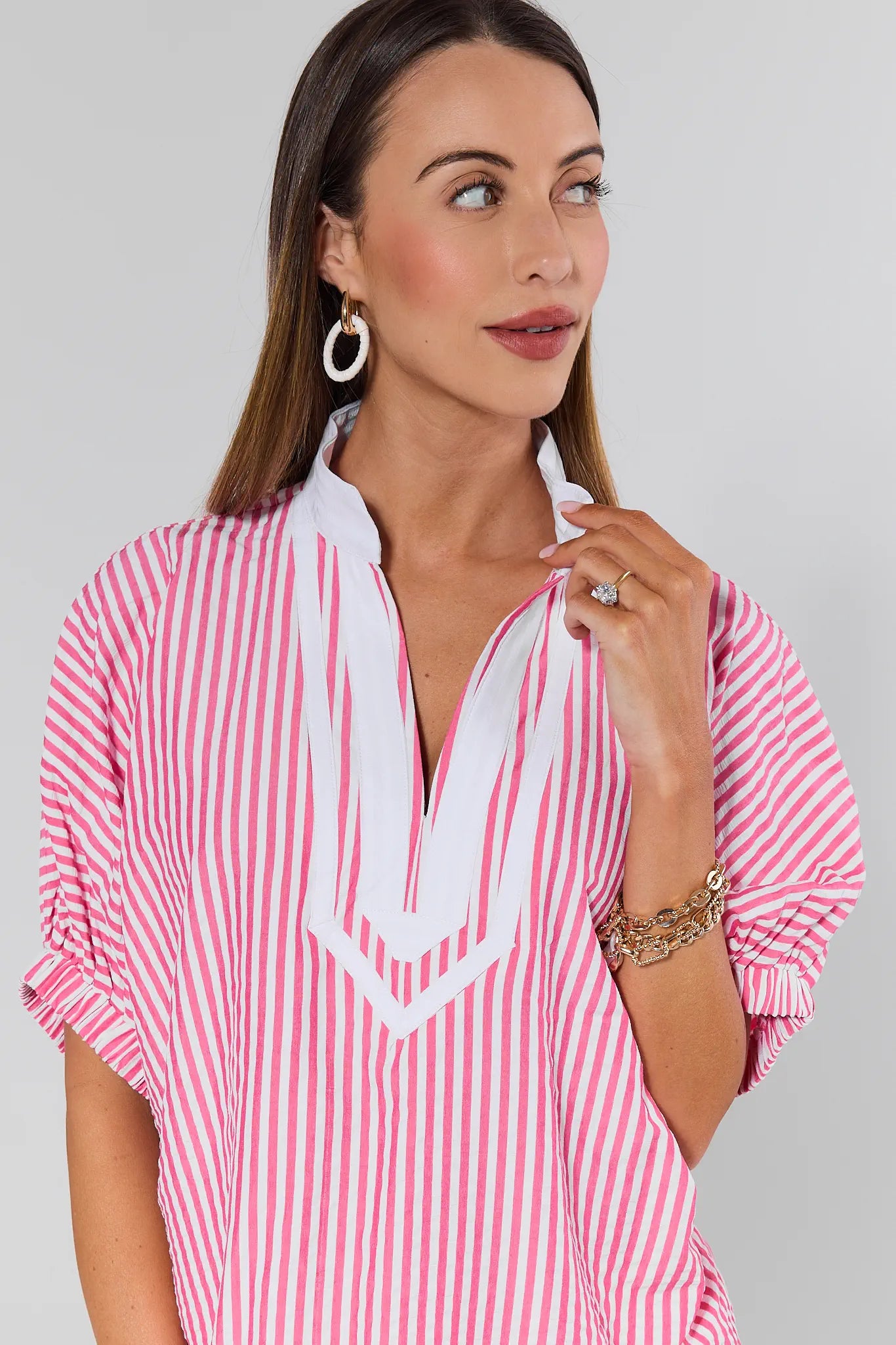 Woman wearing a pink and white striped shirt against a gray background